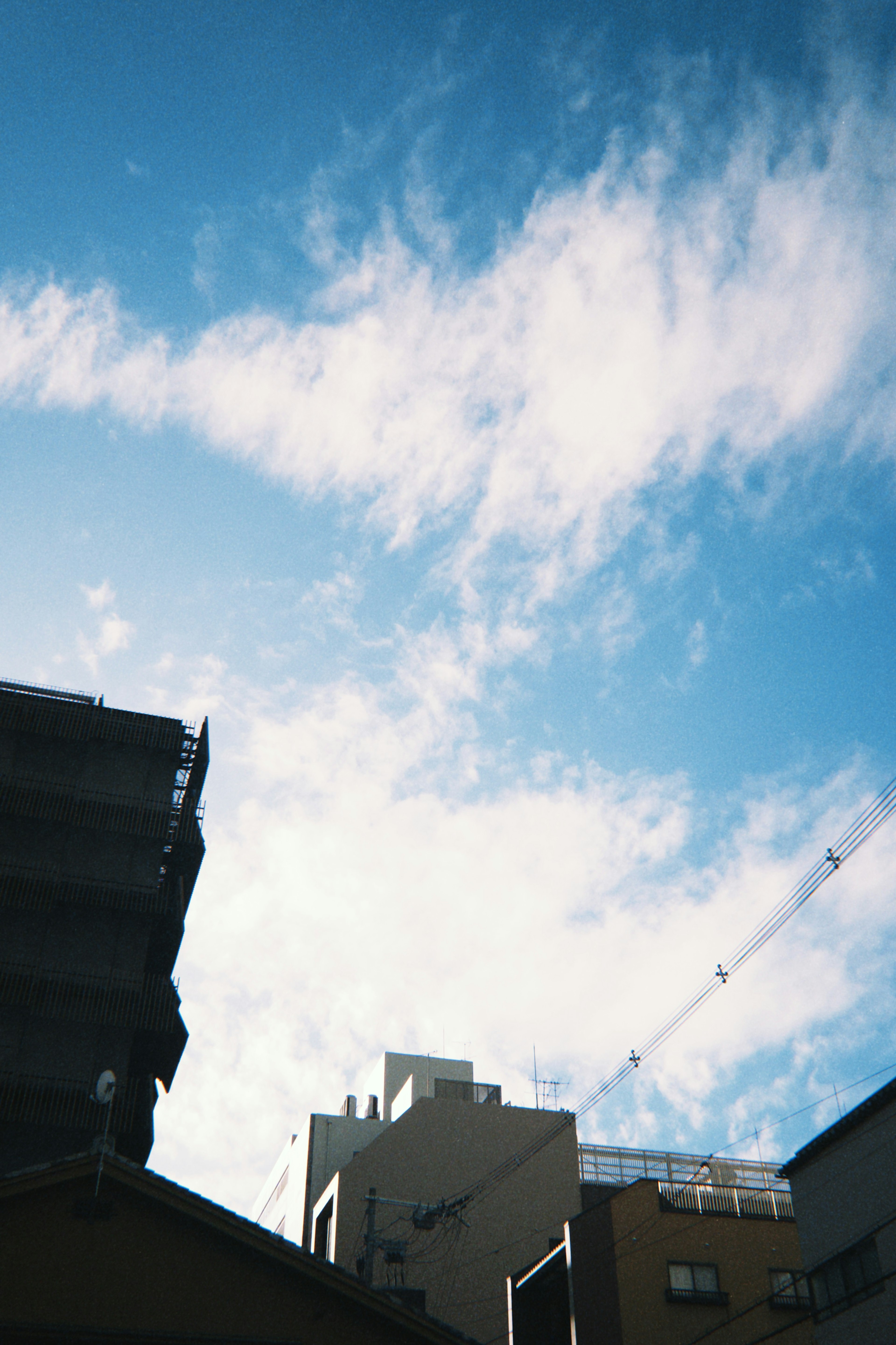 Silueta de edificios contra un cielo azul con nubes blancas