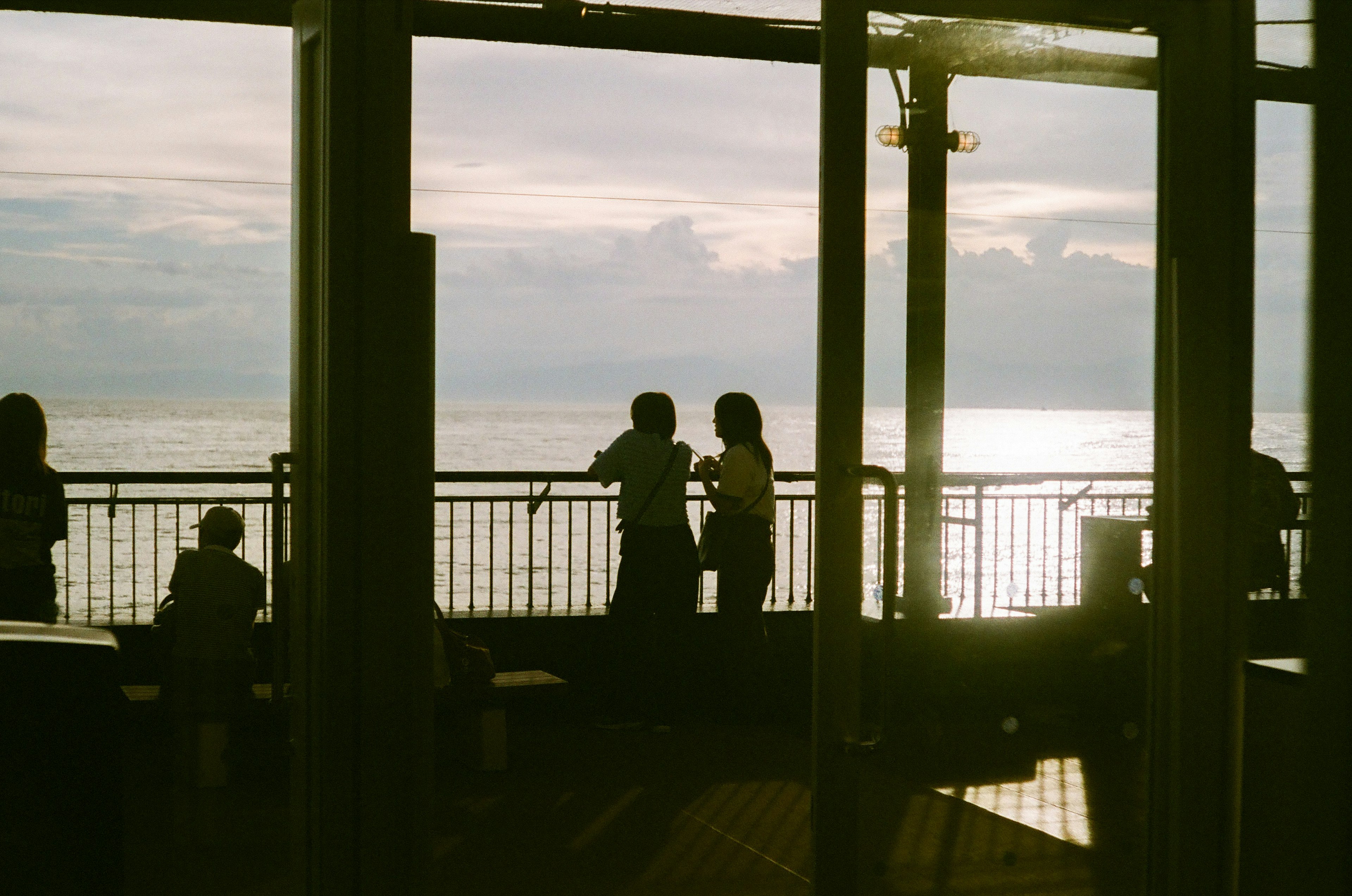 Silueta de una pareja contra un océano al atardecer con otras personas