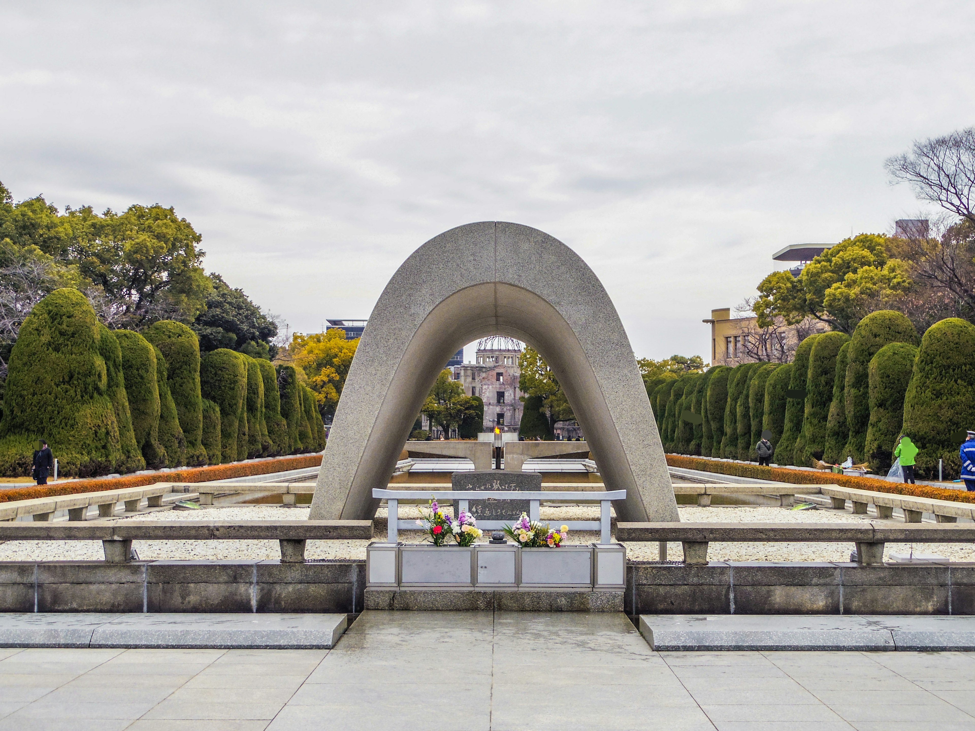 Bogenförmiges Denkmal in einem Park mit gepflegten Hecken und Blumen