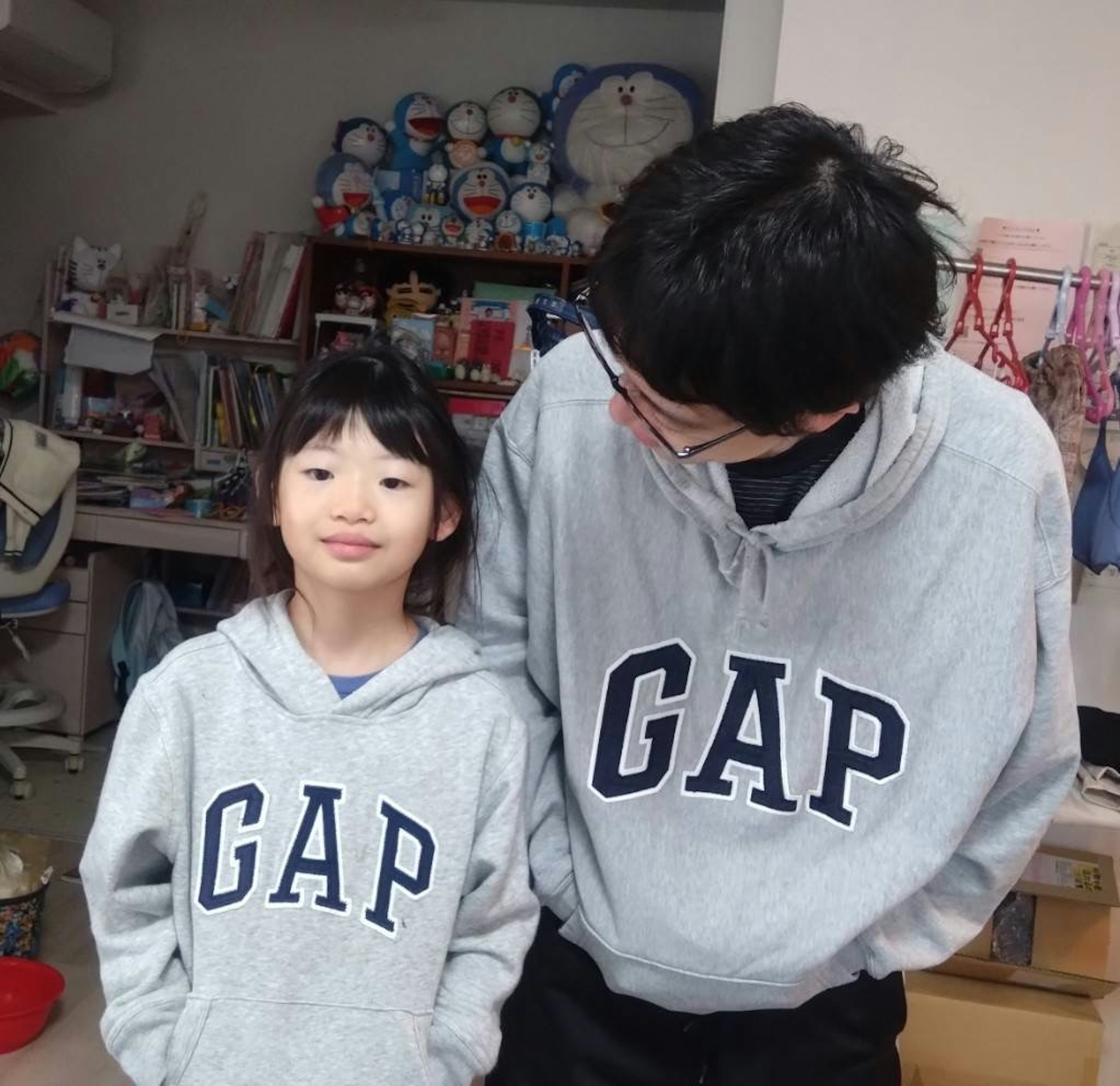 灰色のGAPパーカーを着た子供と大人が微笑んでいる室内の写真