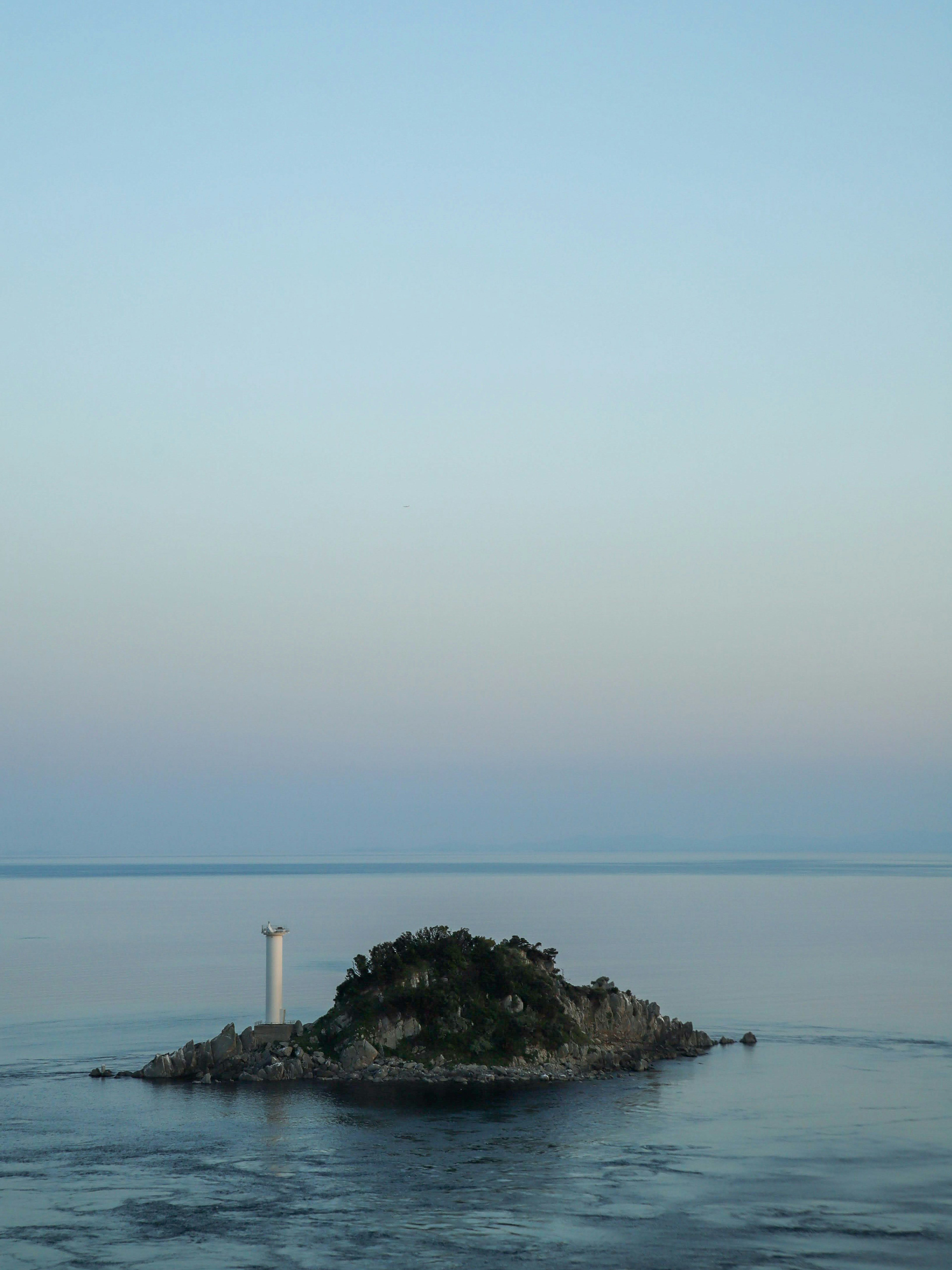 Vue sereine d'une petite île avec un phare blanc dans des eaux calmes