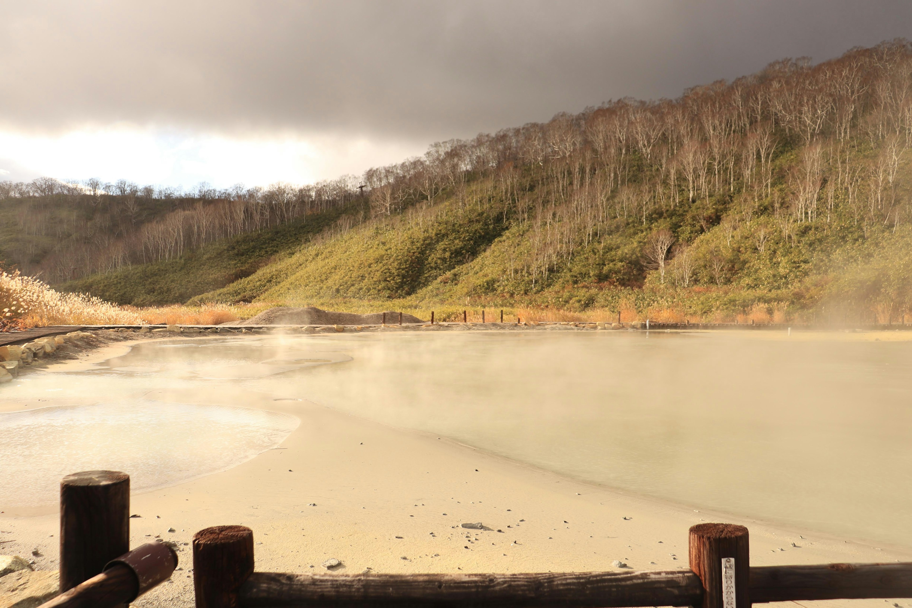 Scenic mountain landscape with steam rising from a hot spring lake