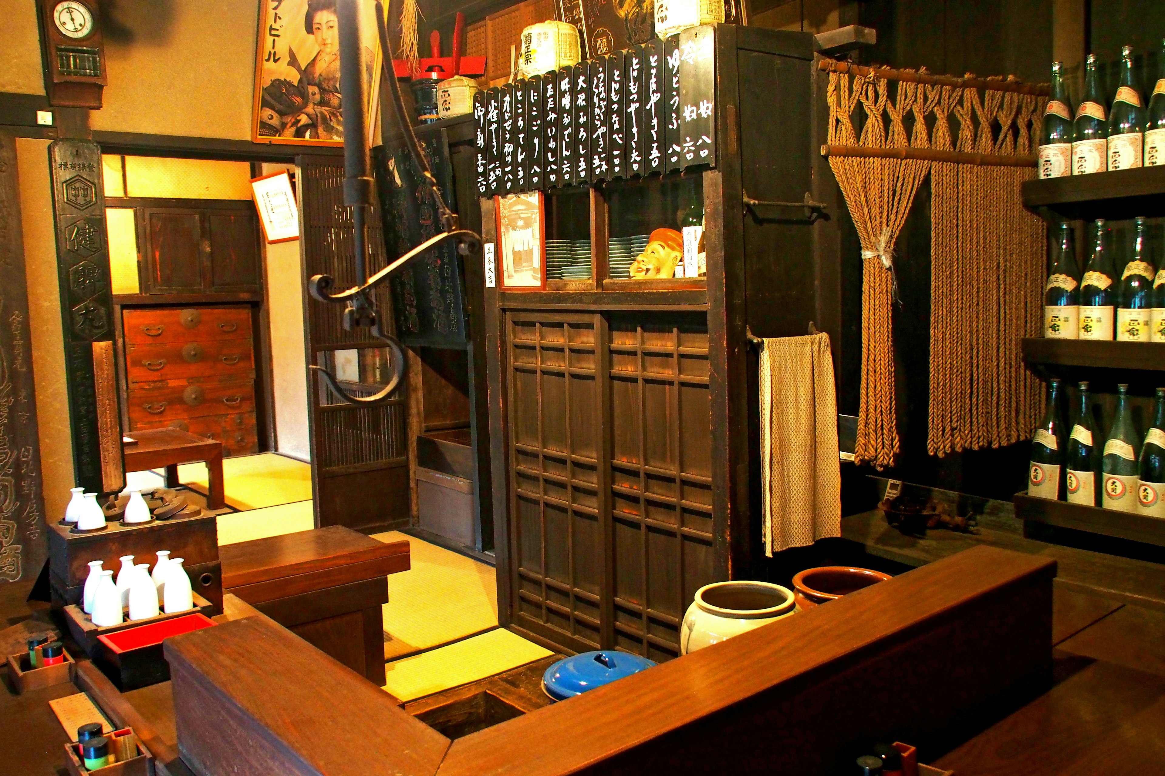 Interior of a traditional Japanese izakaya featuring wooden counter and shelves with sake bottles