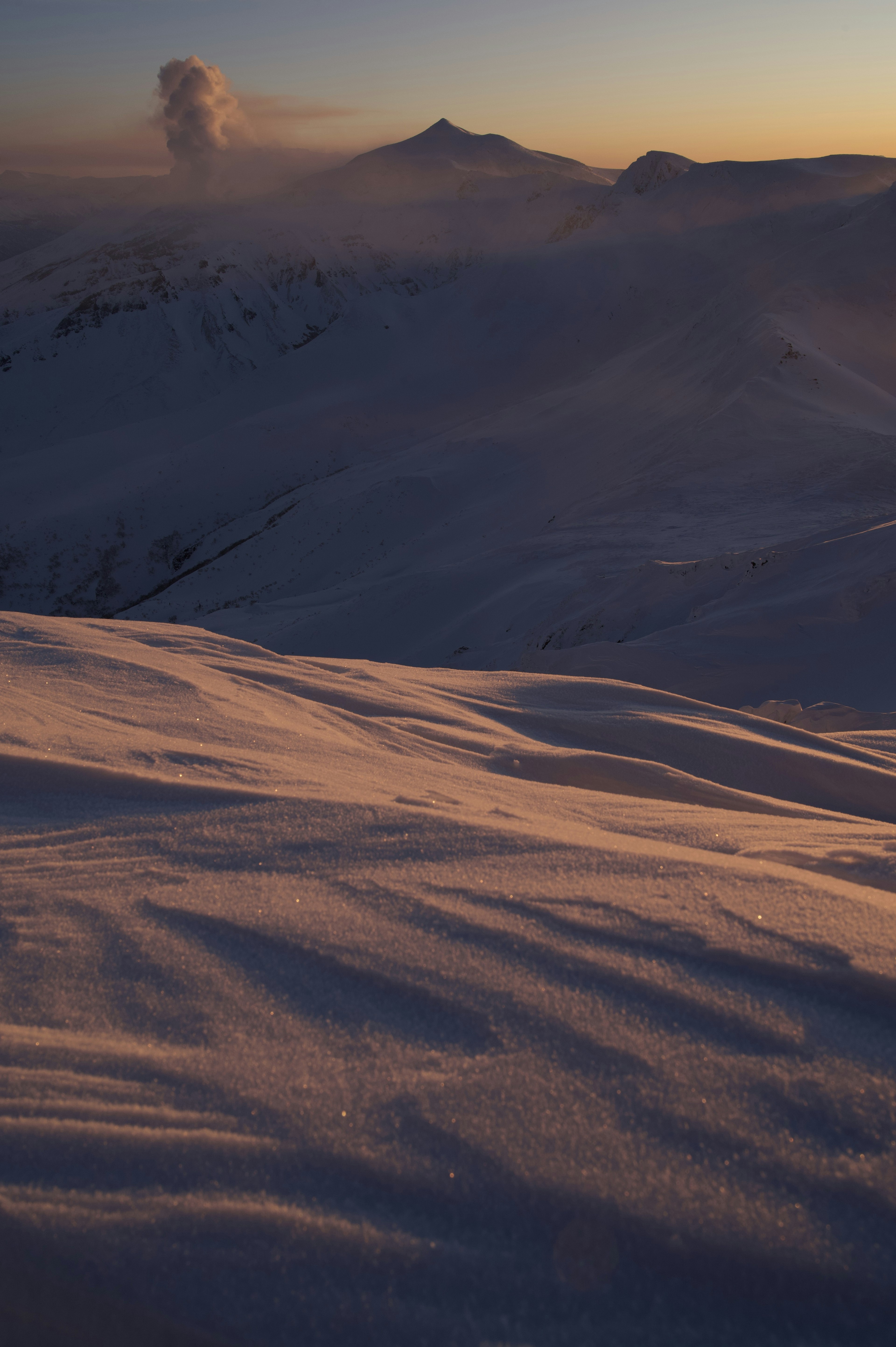 Paysage de montagne enneigée avec de la fumée s'élevant d'un volcan