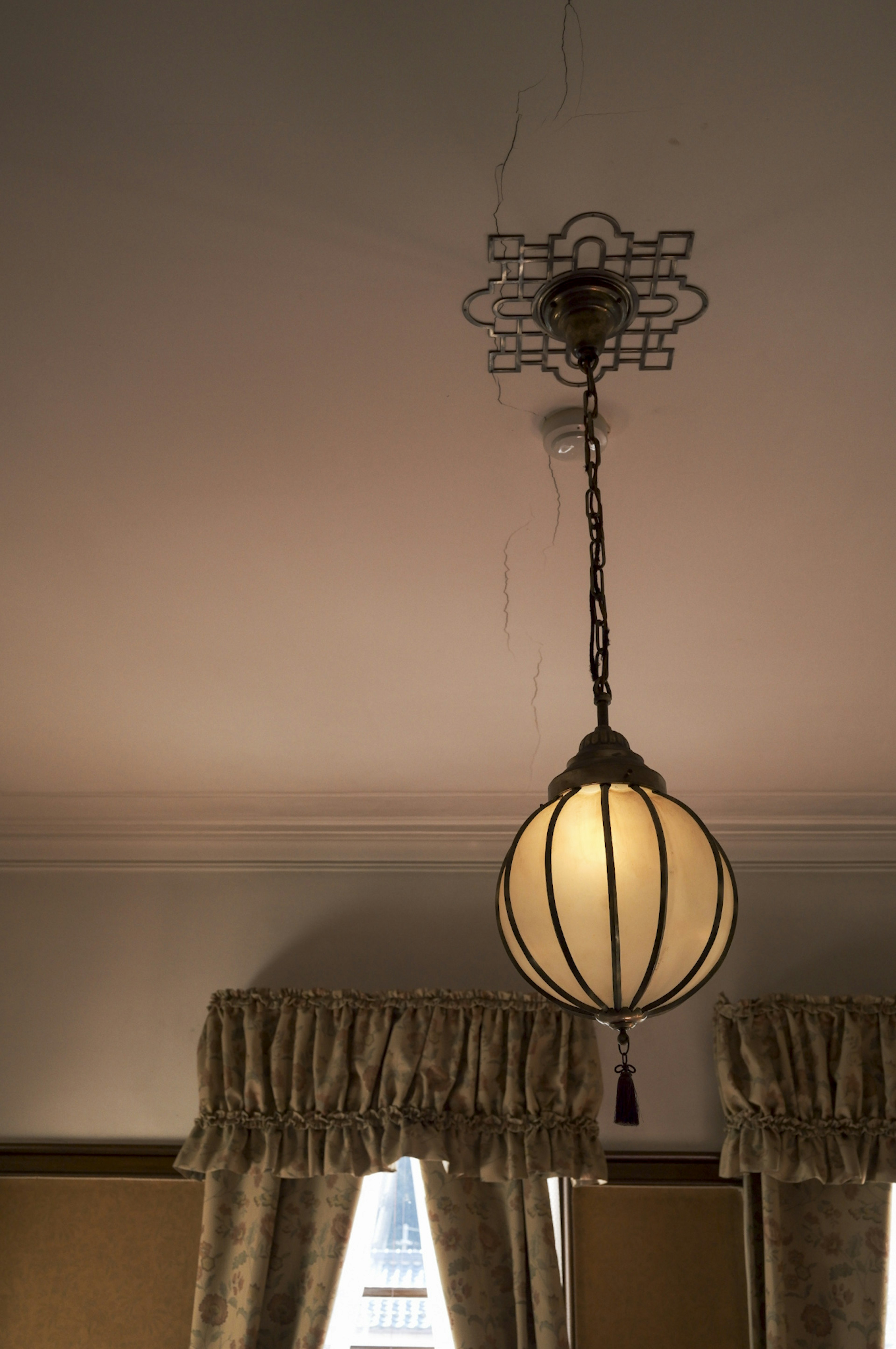 Beautiful pendant lamp hanging from the ceiling with elegant curtains in the background