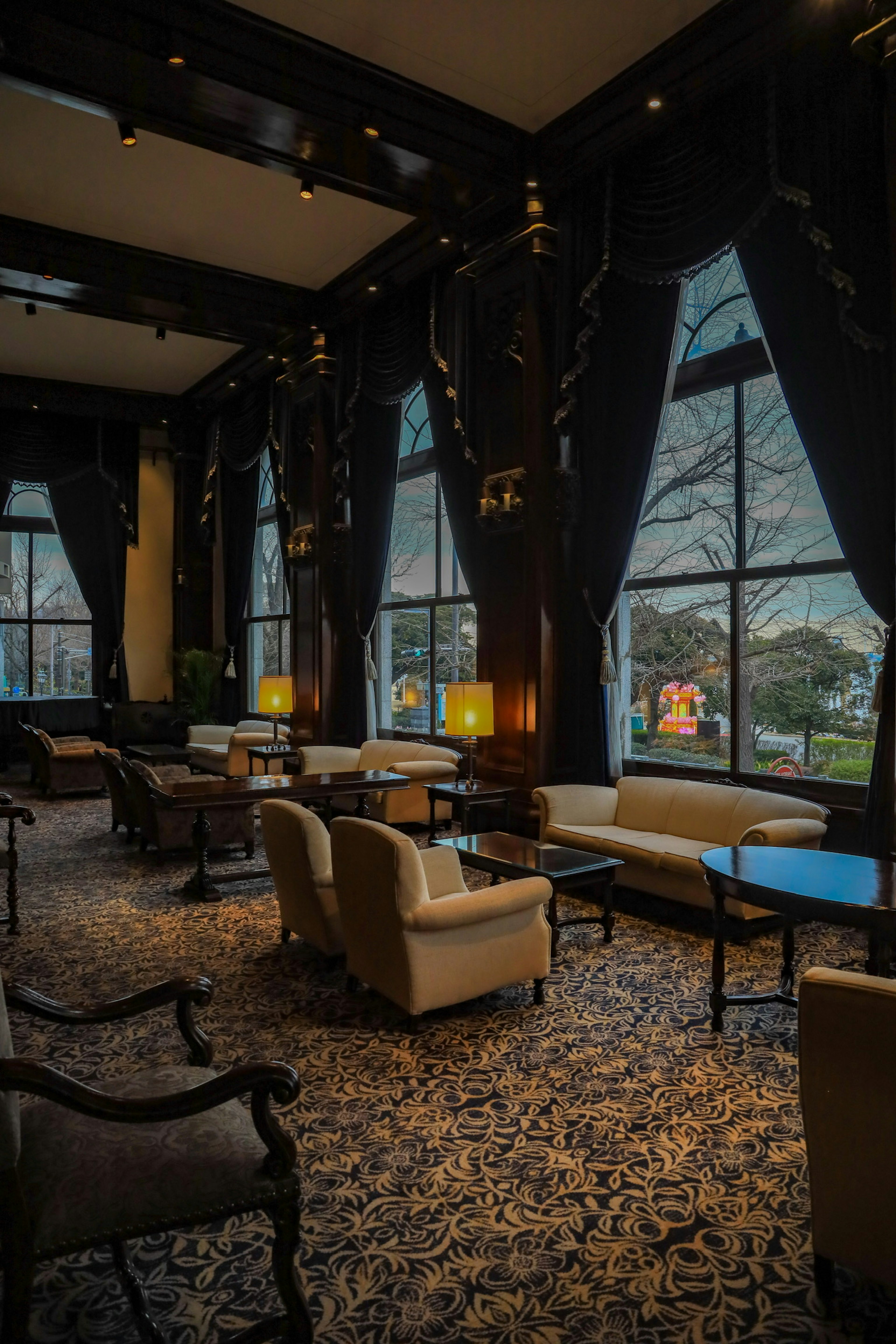 Luxurious lobby interior with dark tones featuring large windows and elegant seating arrangements