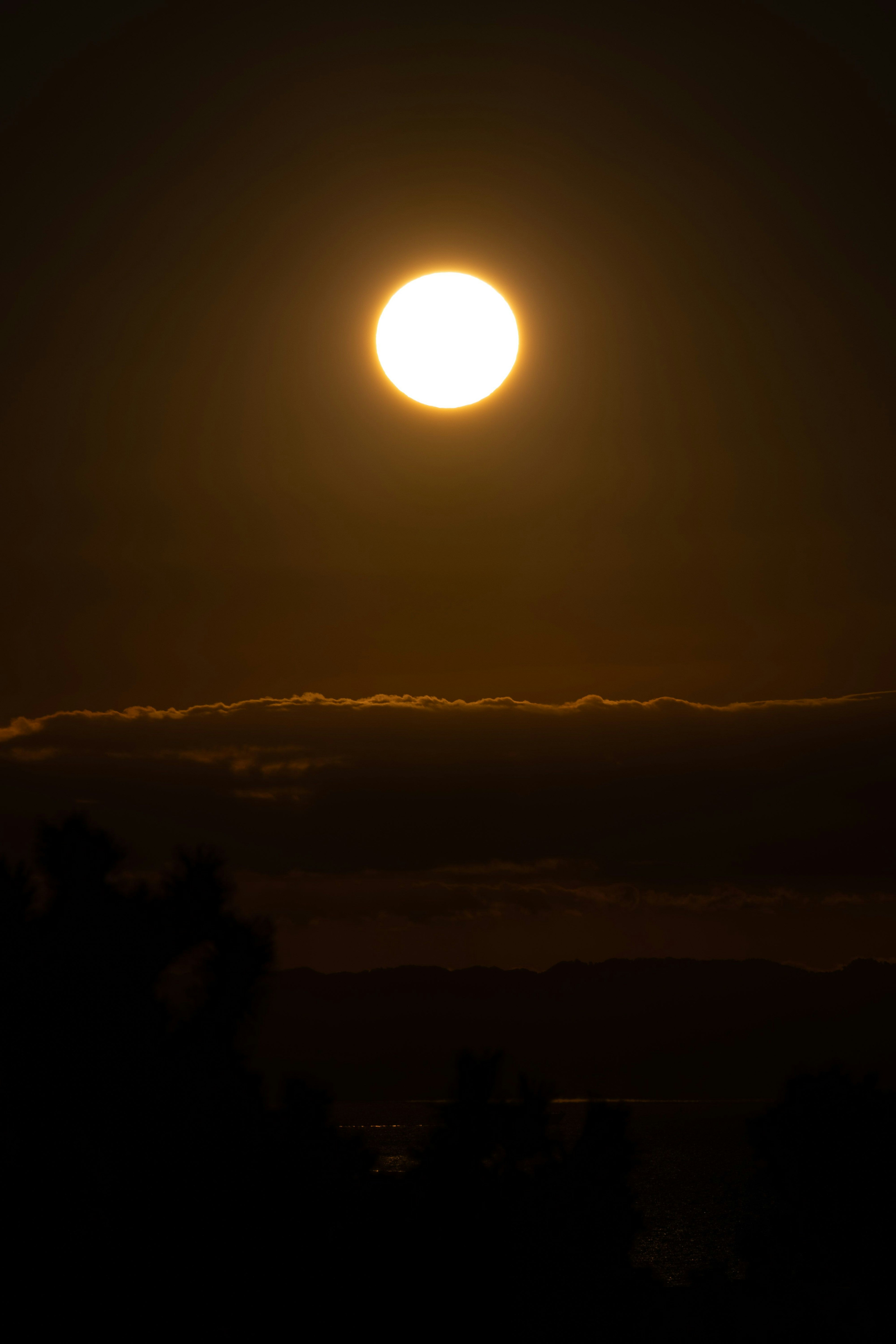 夕暮れ時の太陽が雲の上に輝いているシルエット