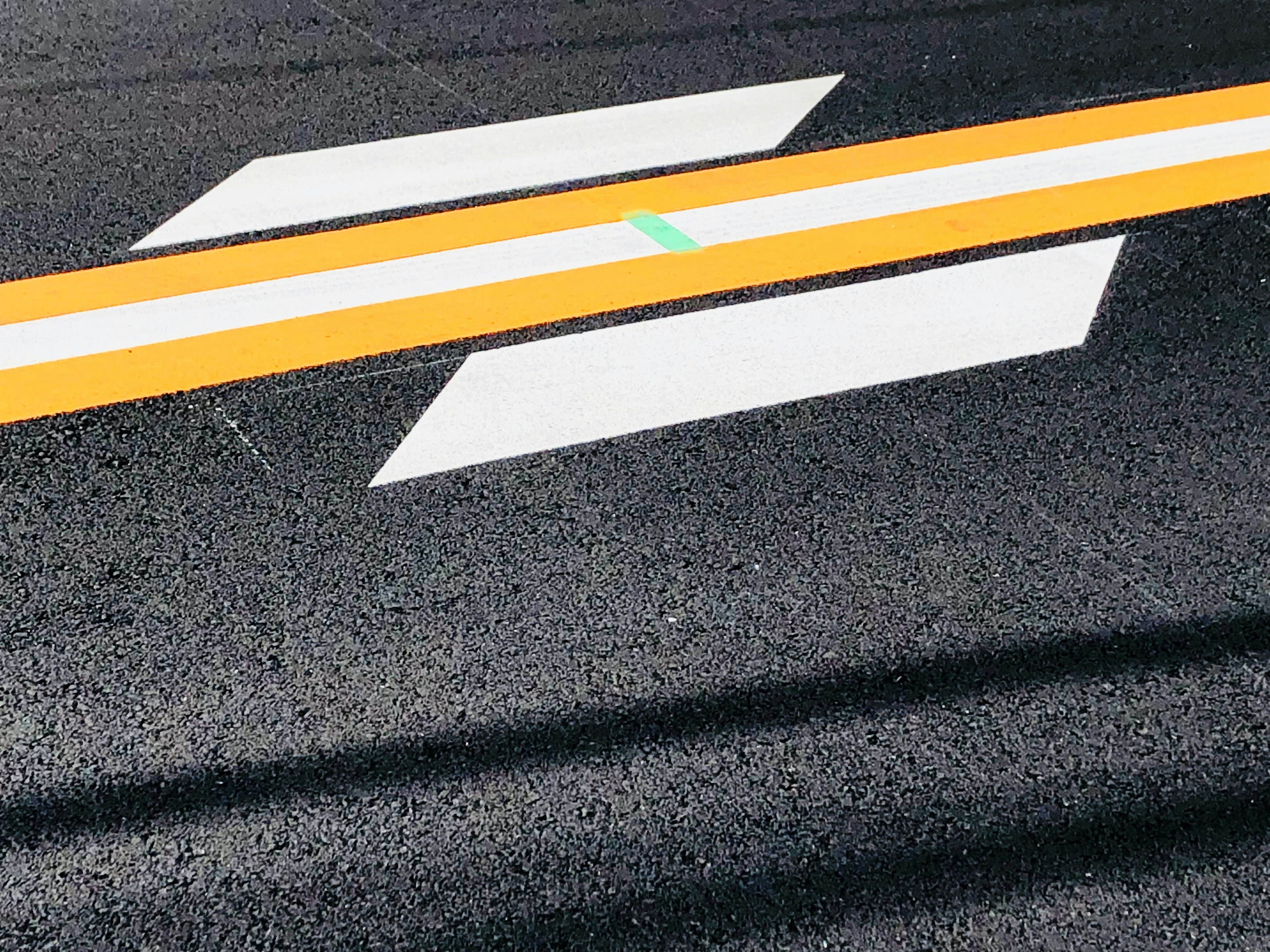 Close-up of asphalt road with yellow line and white arrow markings