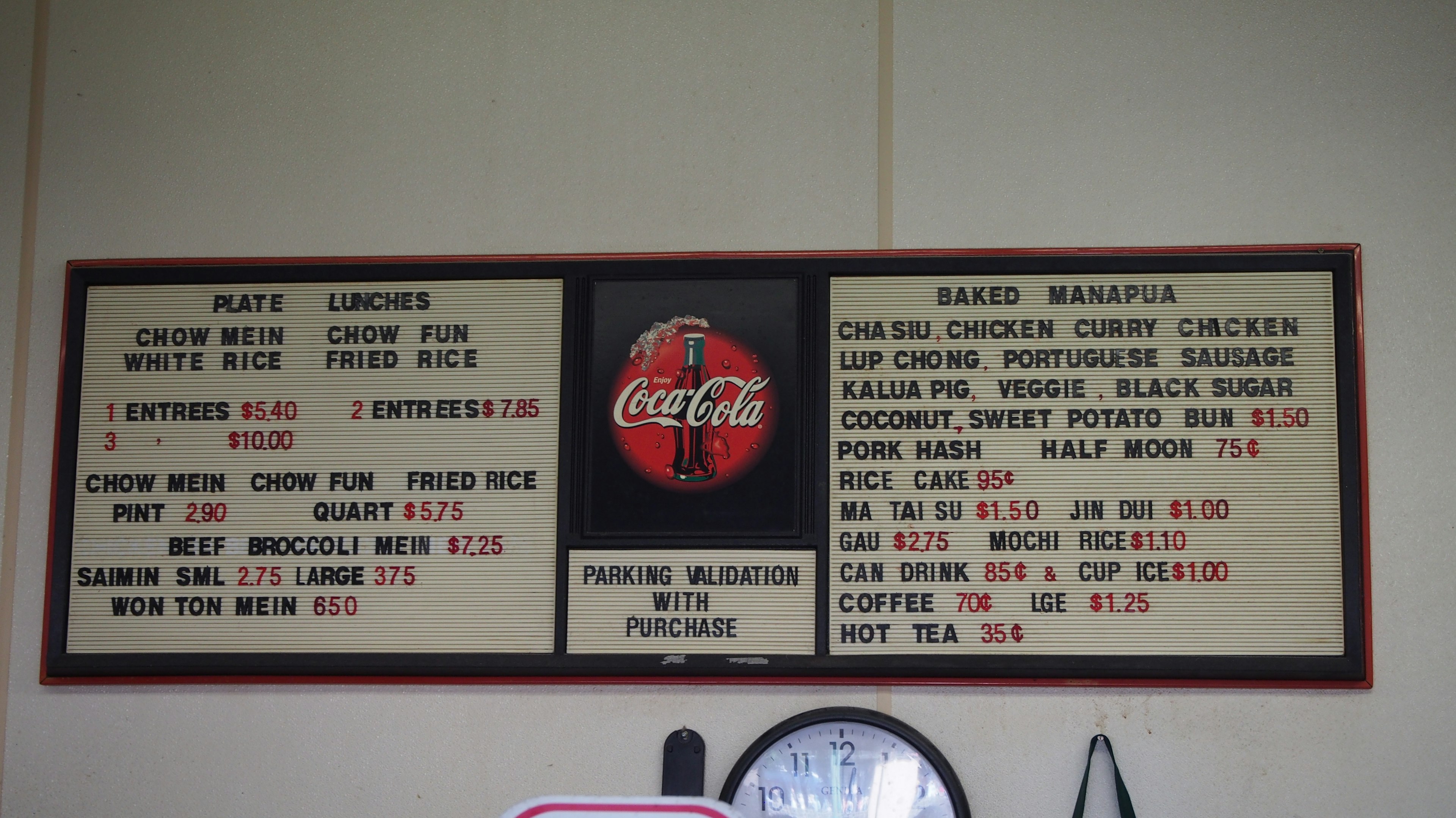 Tablero de menú con el logo de Coca-Cola que enumera precios de alimentos y bebidas