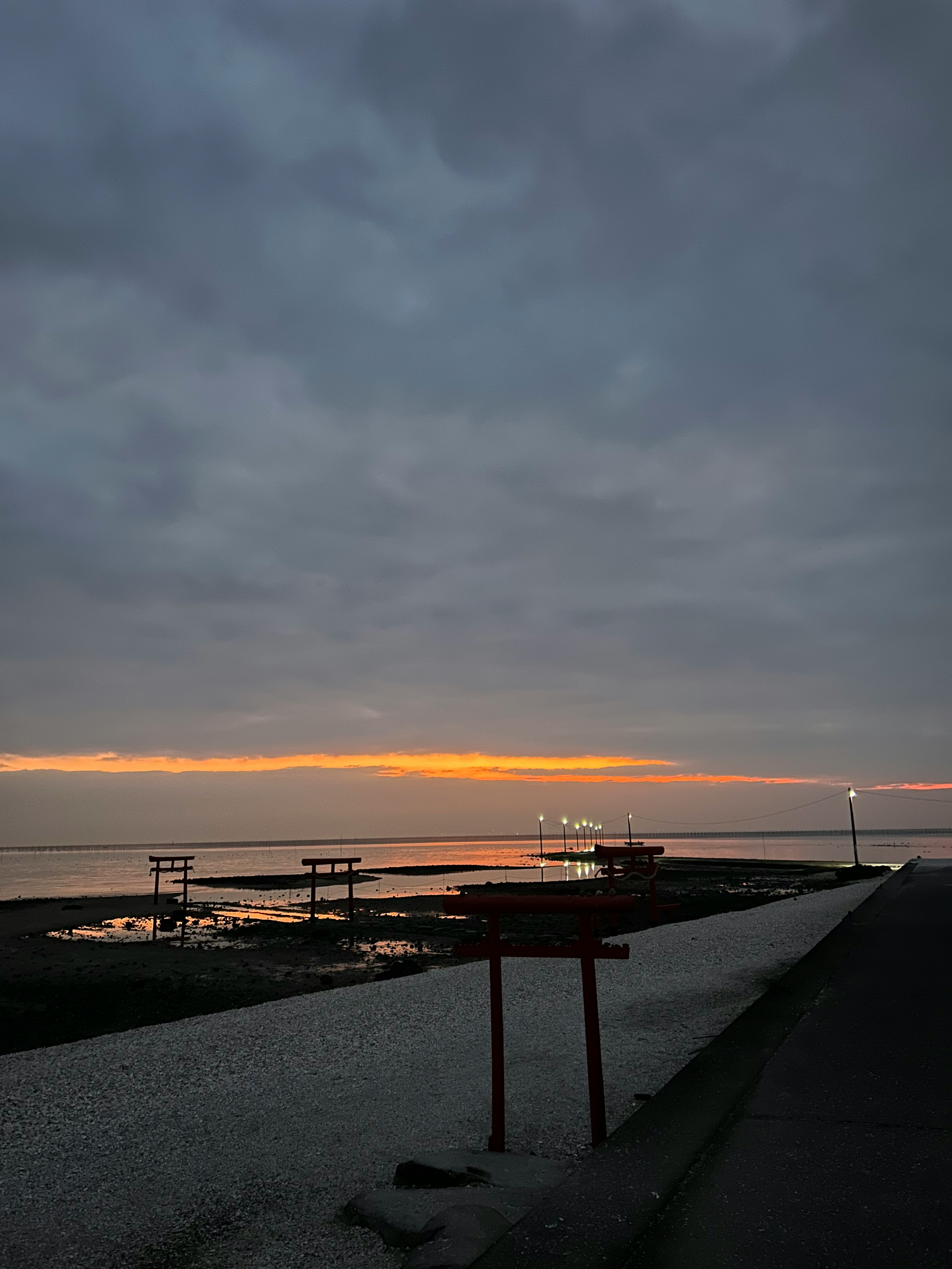 夕焼けの海岸線に沿った静かな風景 灰色の雲とオレンジ色の夕日が映える