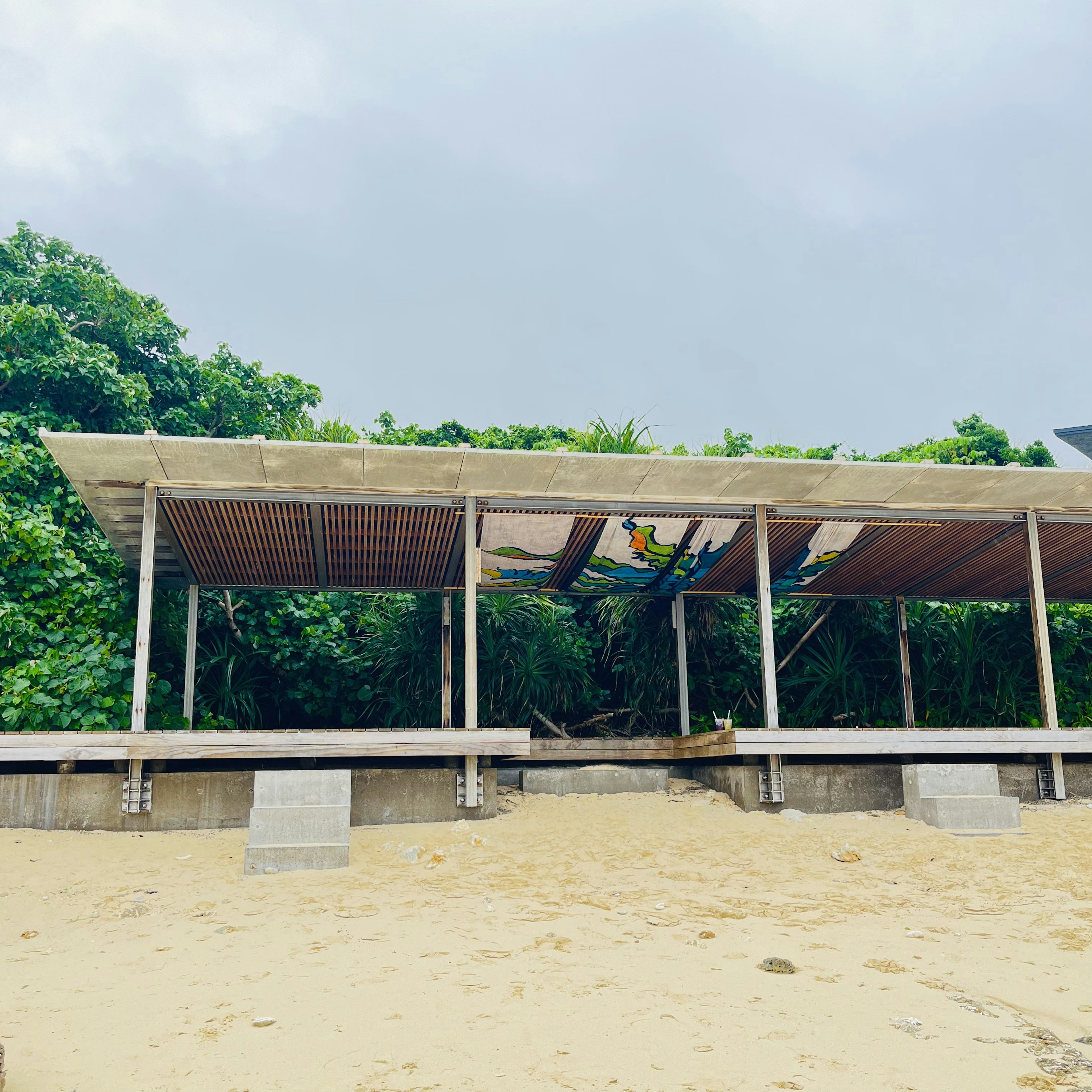 Paviliun kayu di pantai dikelilingi oleh tanaman hijau