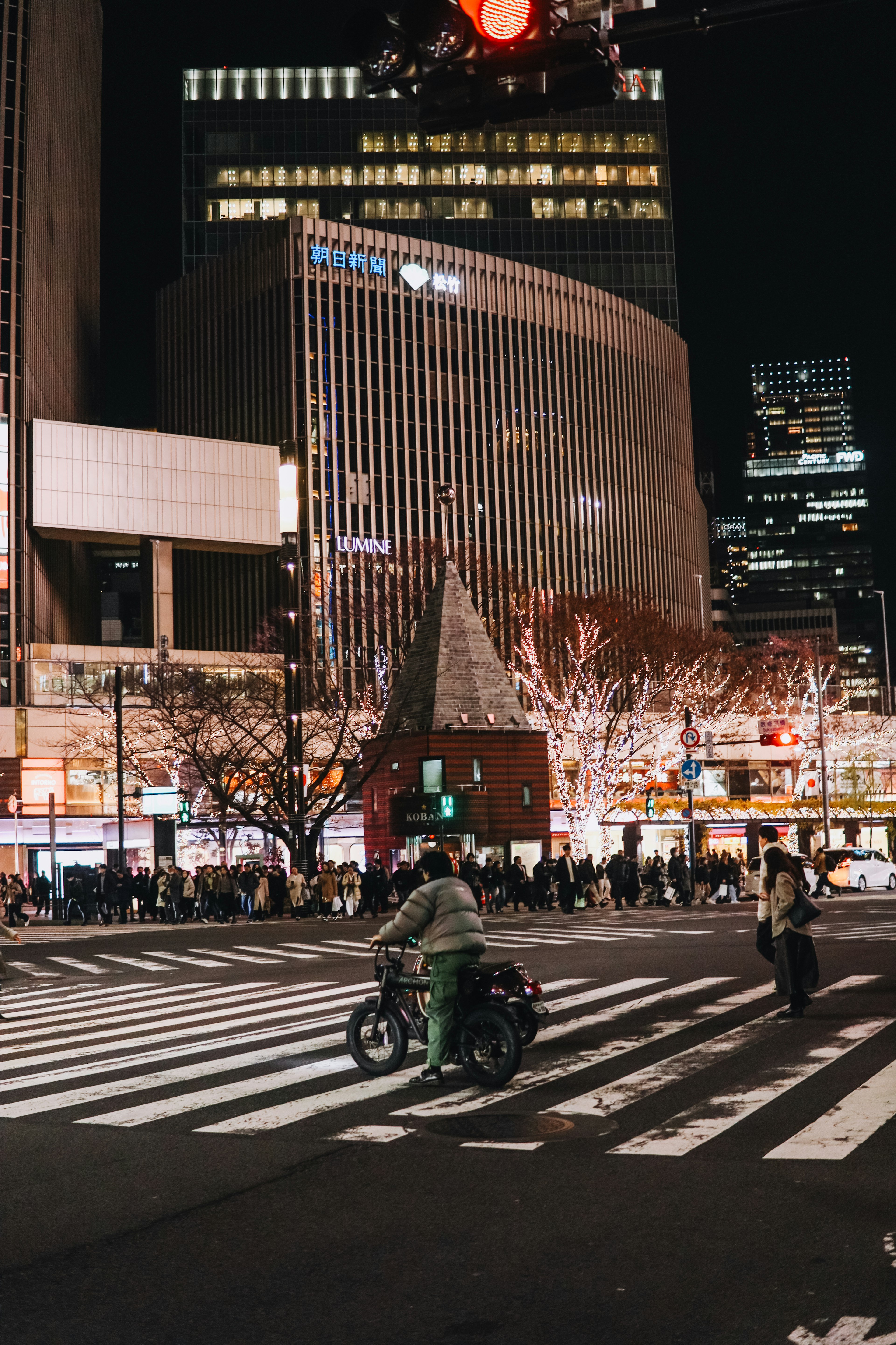 夜の交差点でバイクに乗る人物と賑やかな街並み