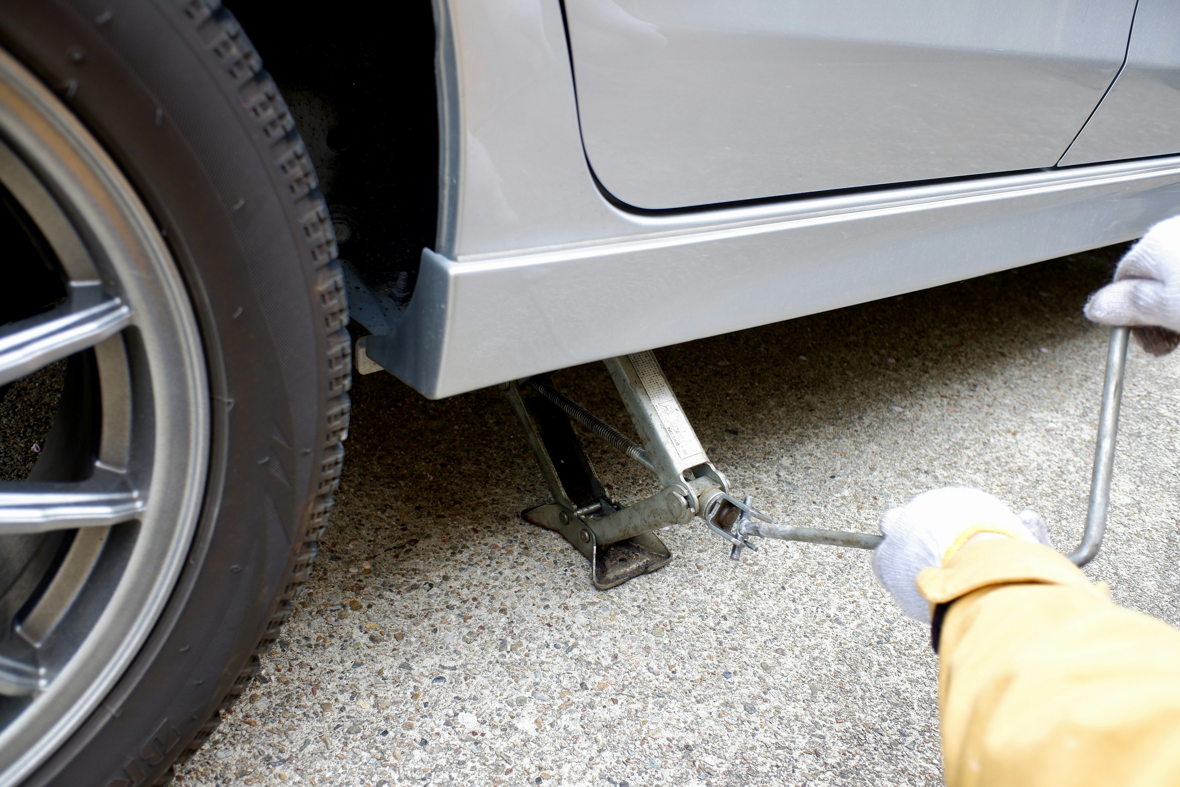 Close-up of a person using a car jack on a vehicle