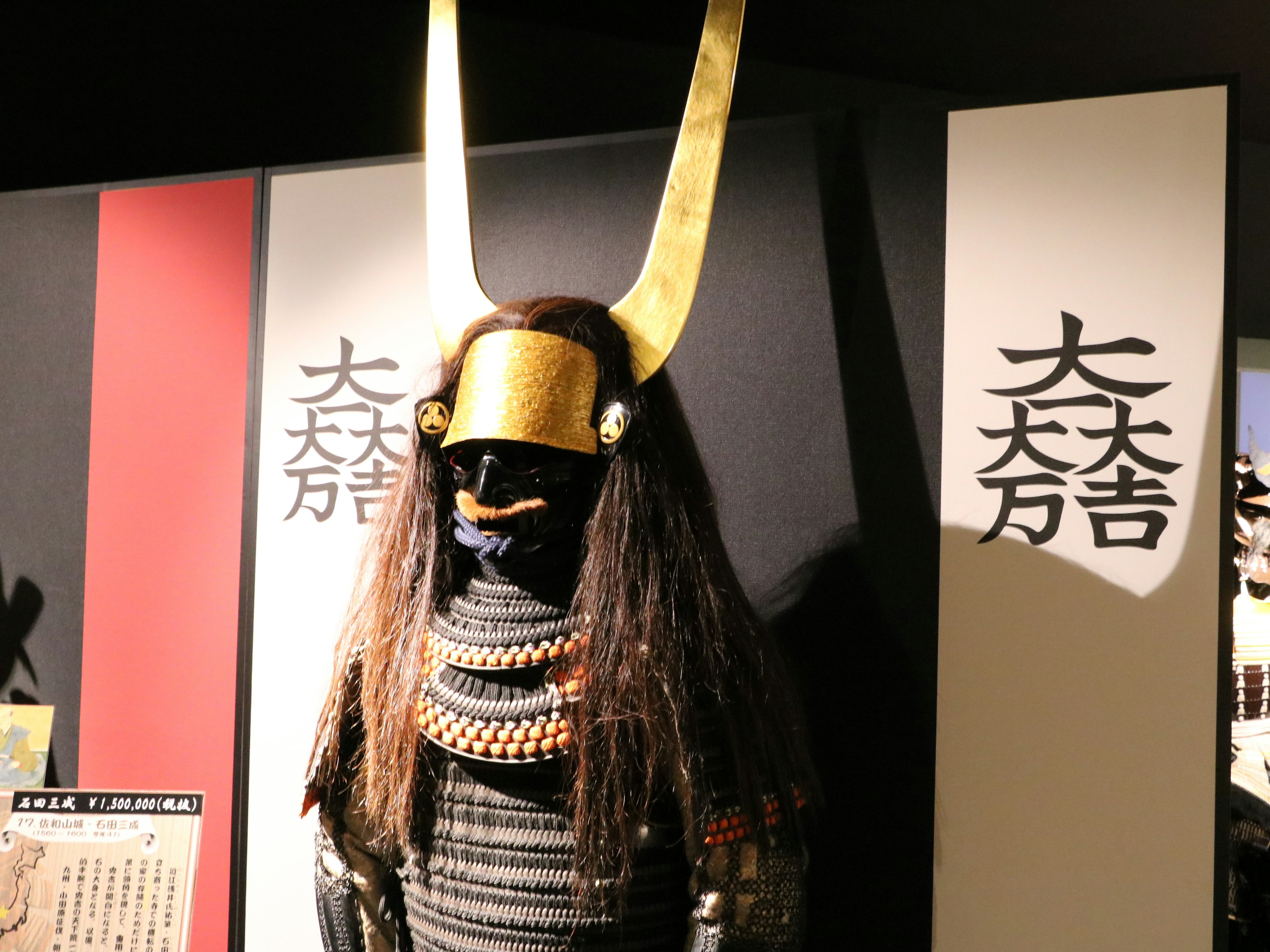 Esposizione di un'armatura da samurai con un elmo dorato e capelli lunghi