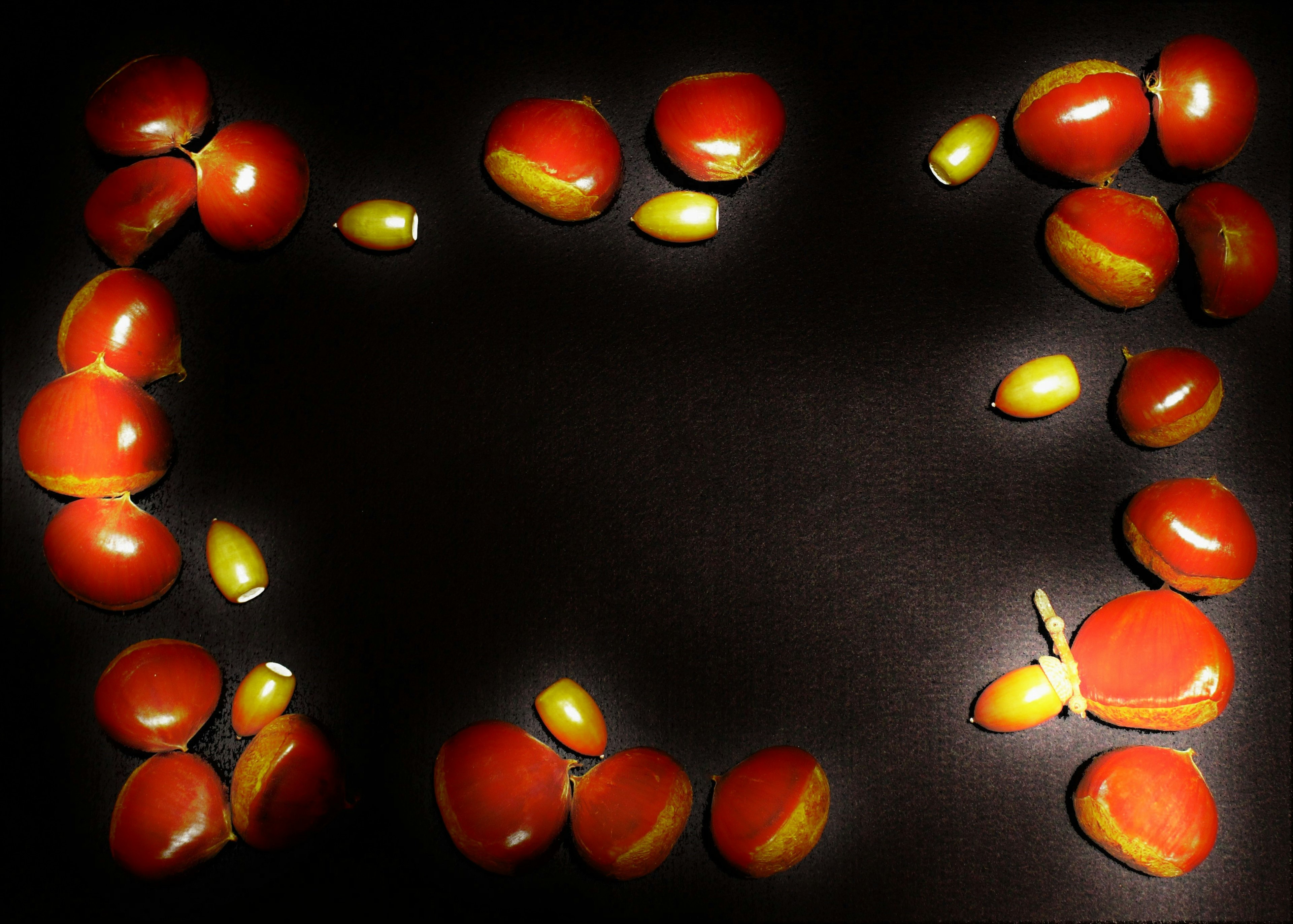 Red fruits and yellow seeds arranged on a black background