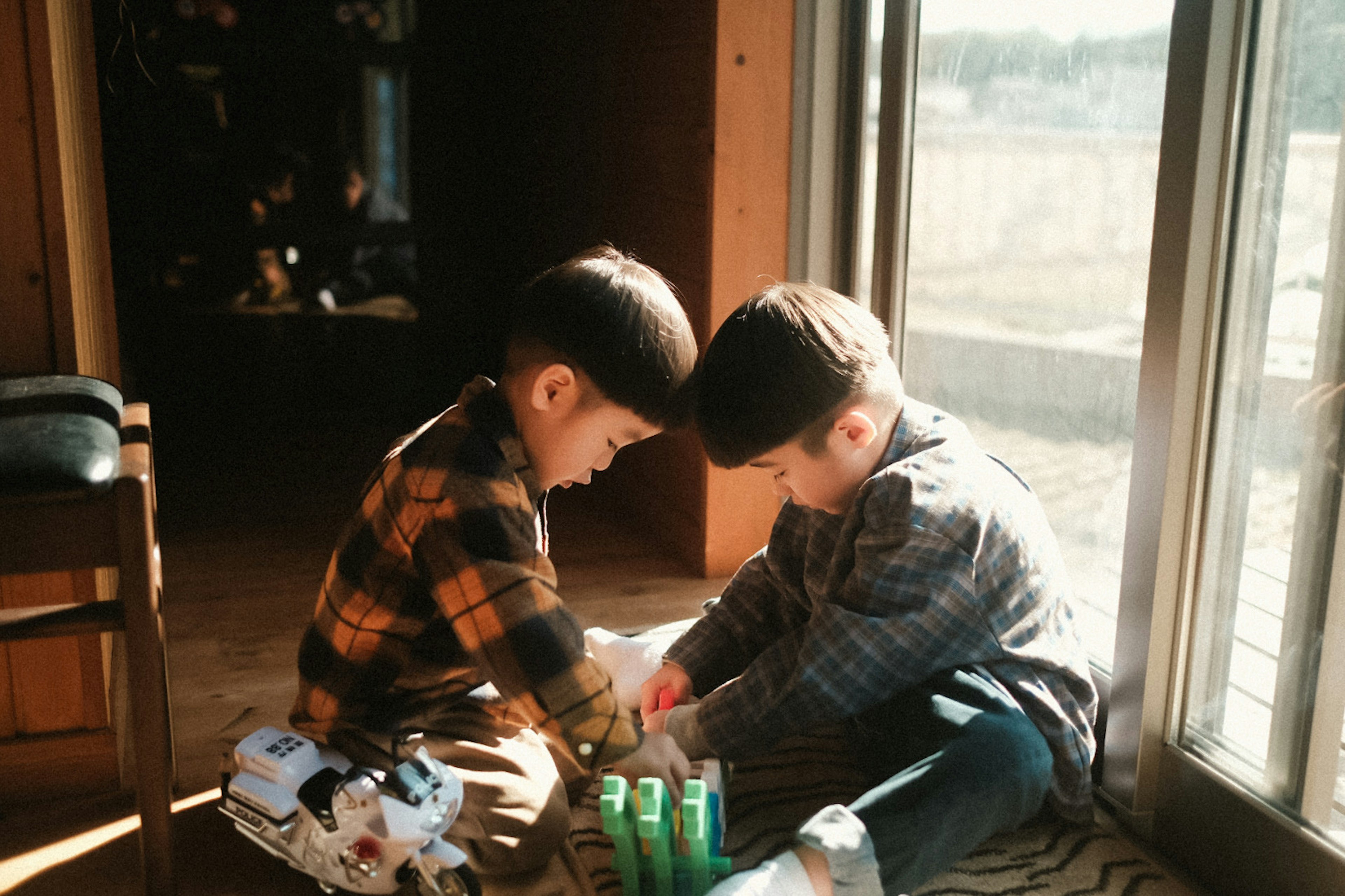 Dos niños jugando cerca de una ventana