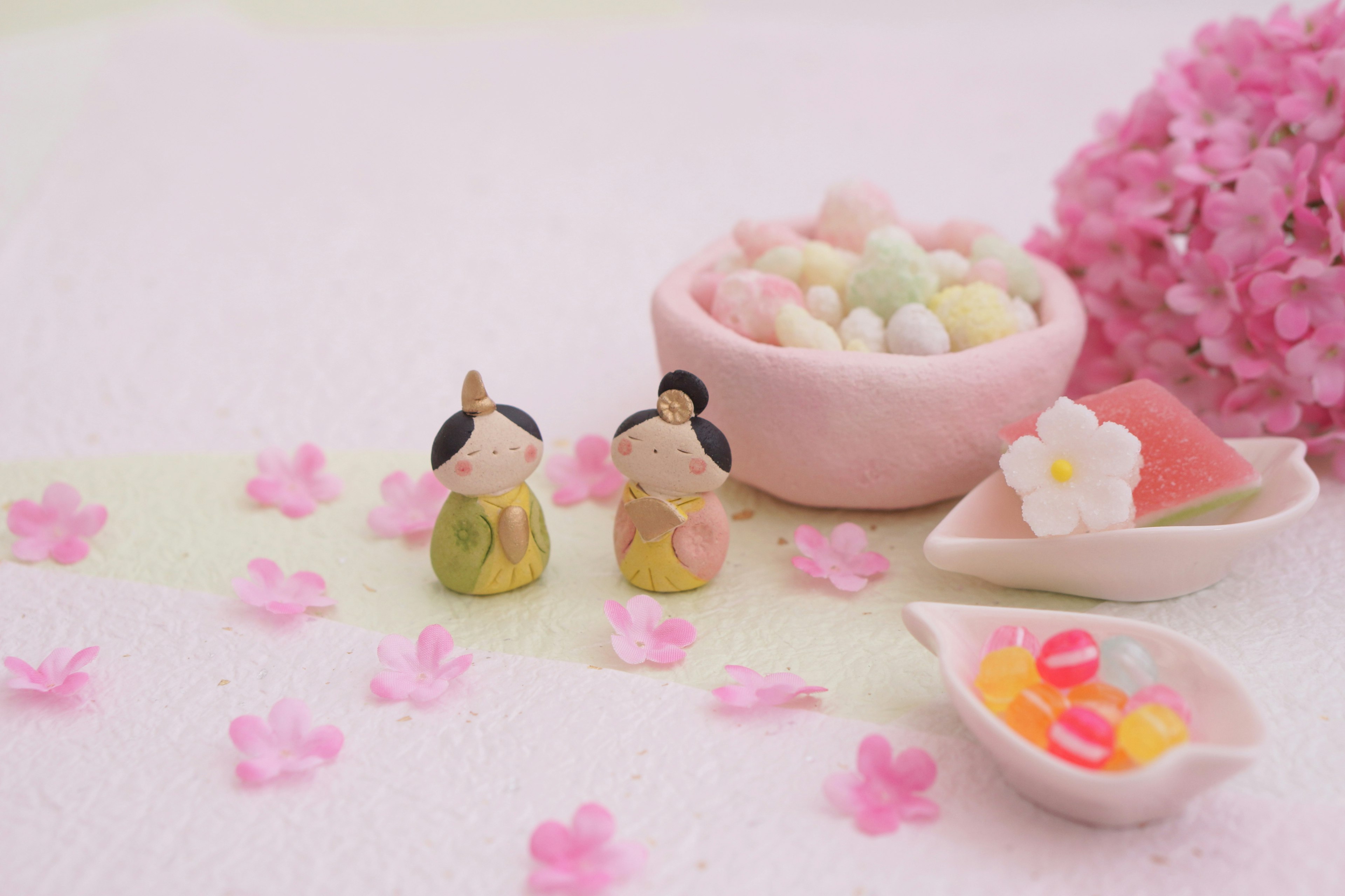 Delicate figurines surrounded by pink petals and colorful candies