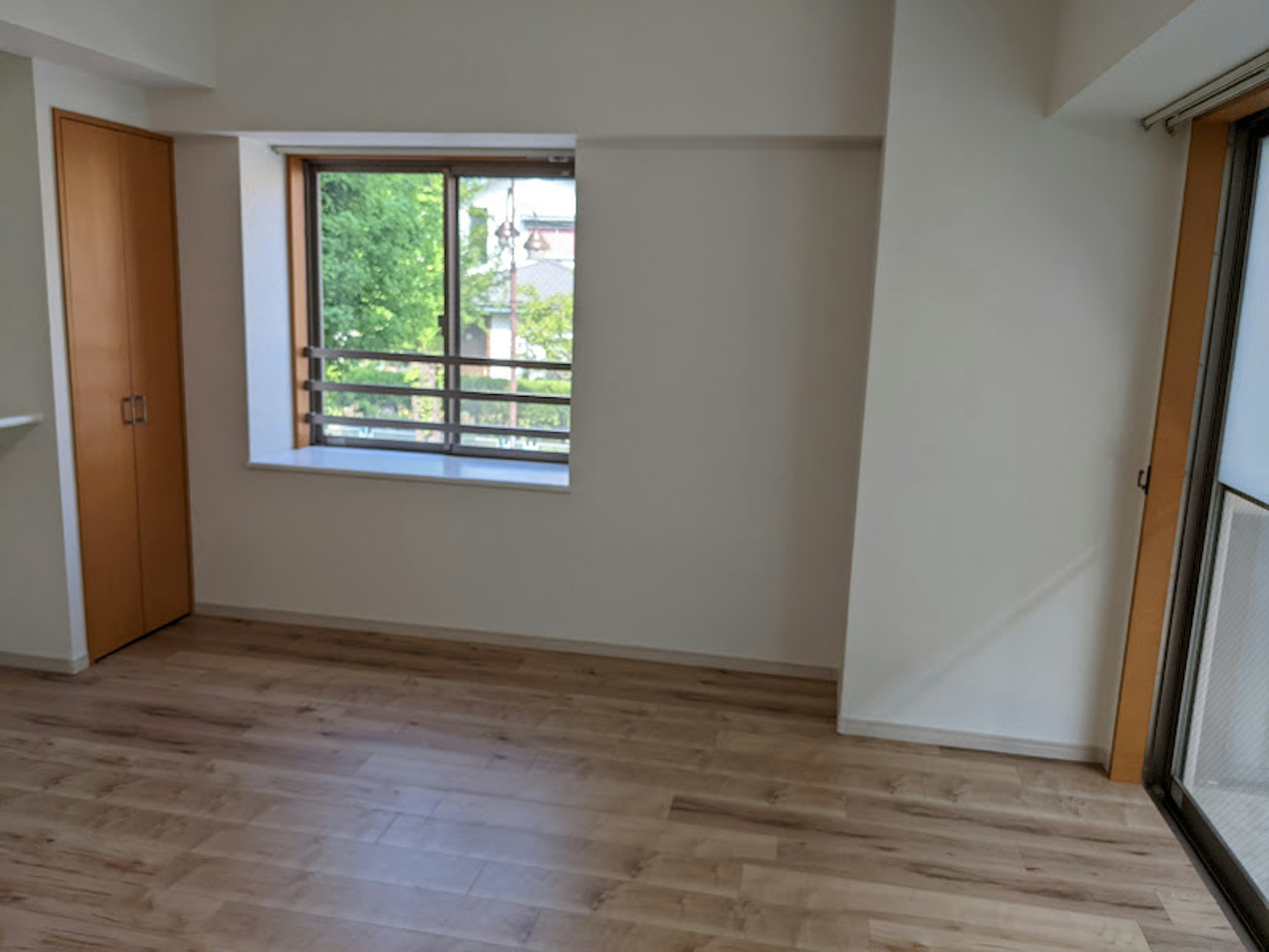 Chambre simple avec un sol en bois clair et une grande fenêtre