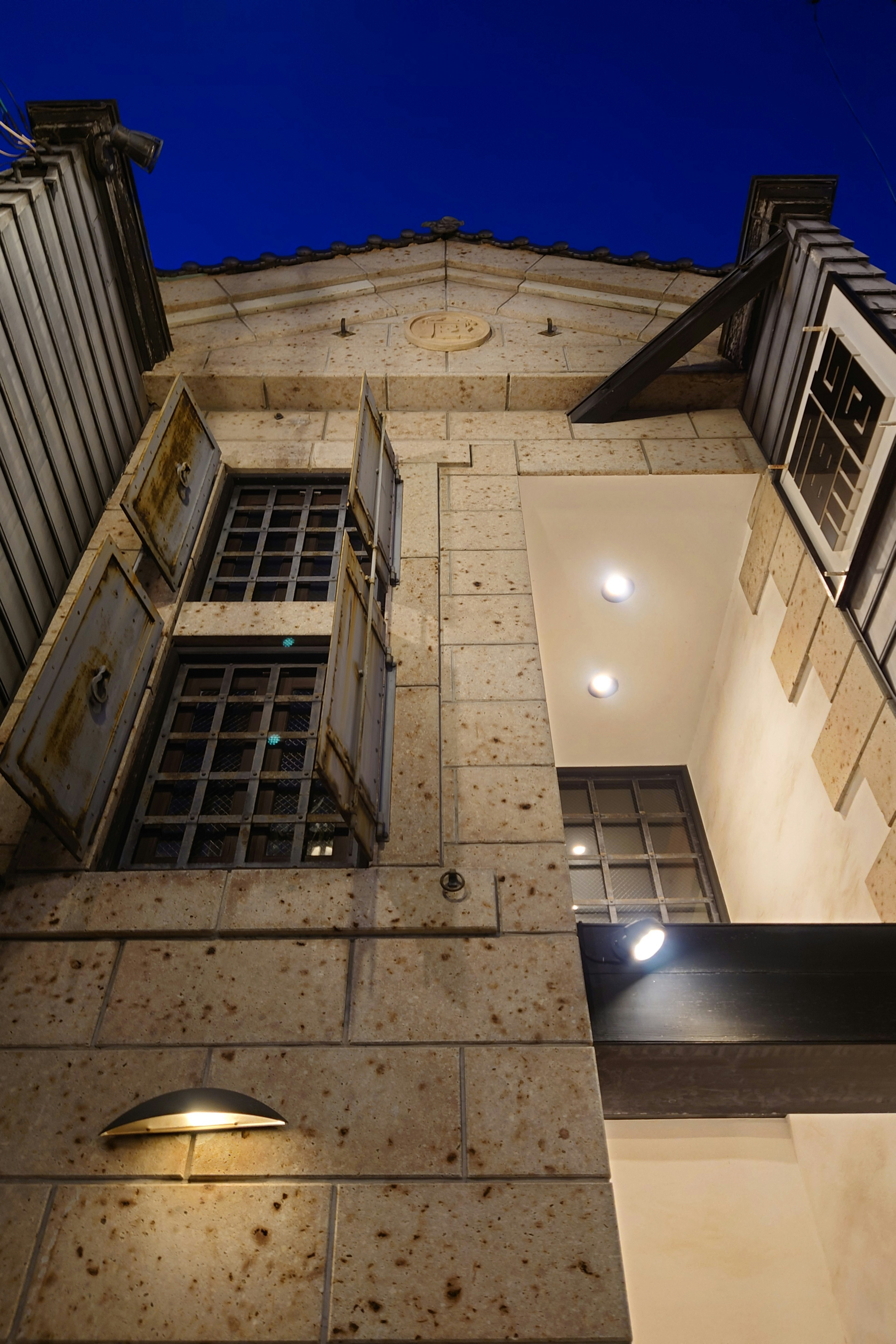 Fachada de piedra de un edificio con ventanas abiertas bajo el cielo nocturno