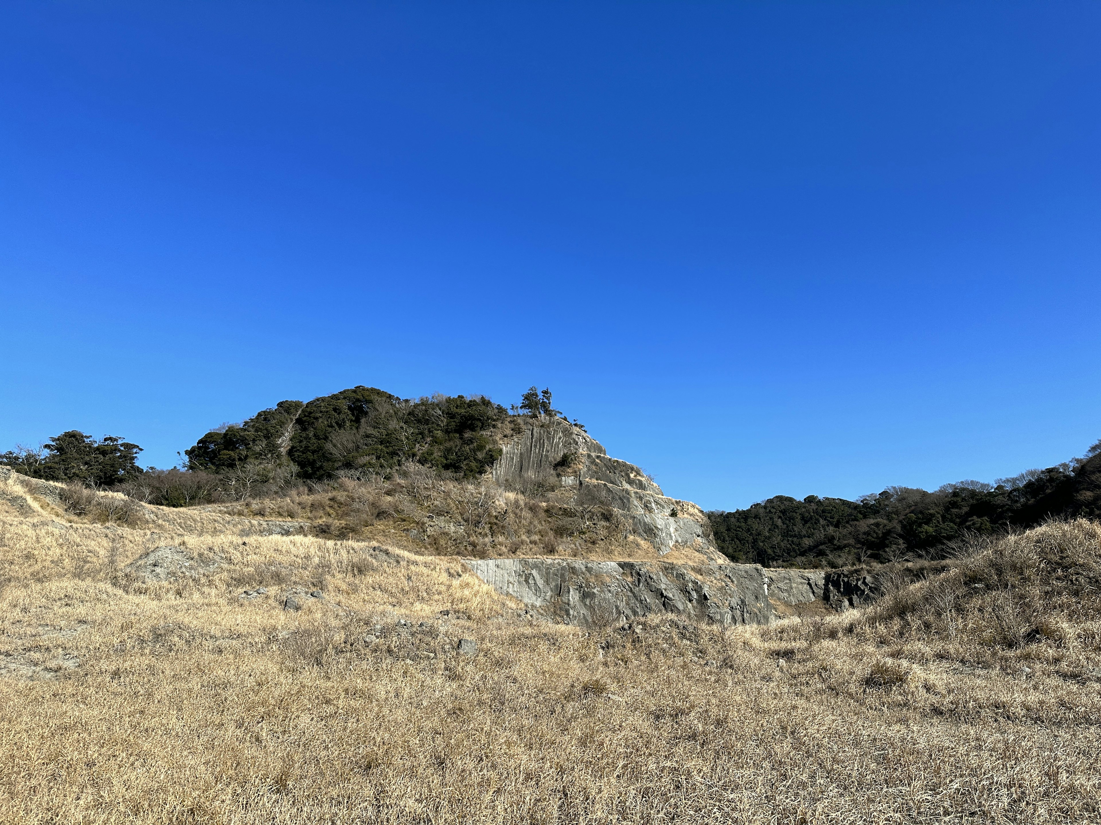 Dry grassland and hill under a blue sky