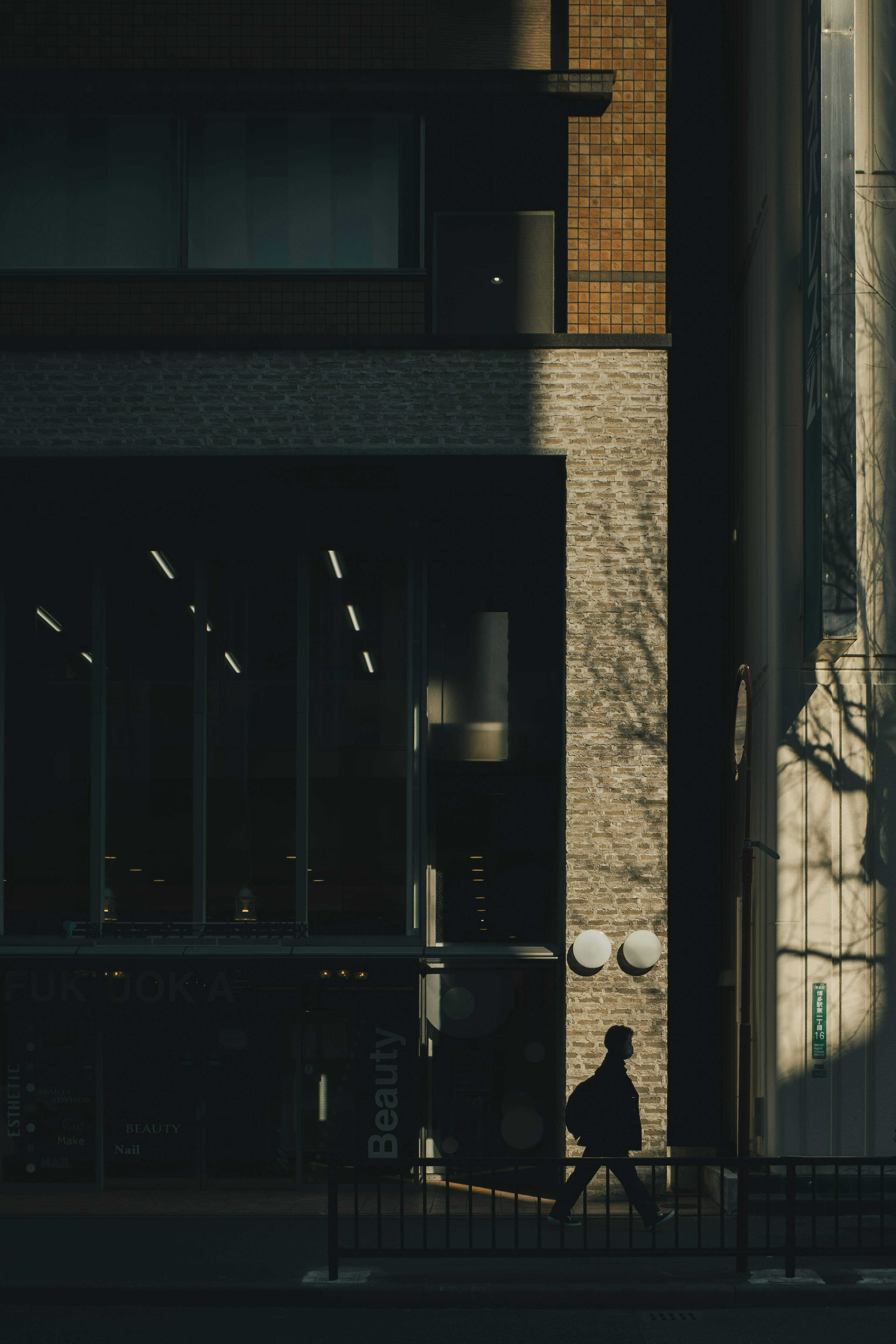 Silueta de una persona caminando junto a un edificio en la sombra