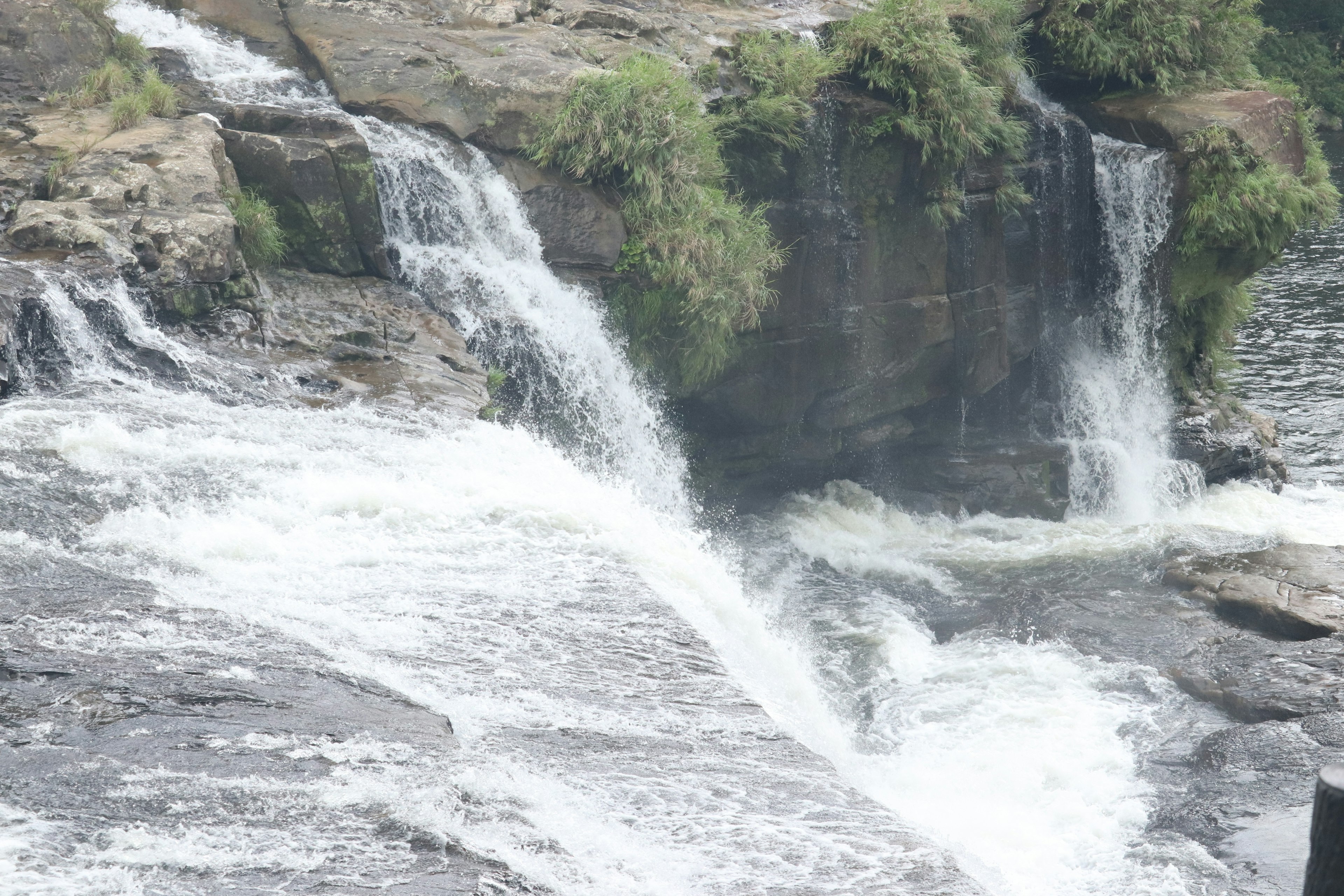 Pemandangan indah air terjun mengalir di antara bebatuan