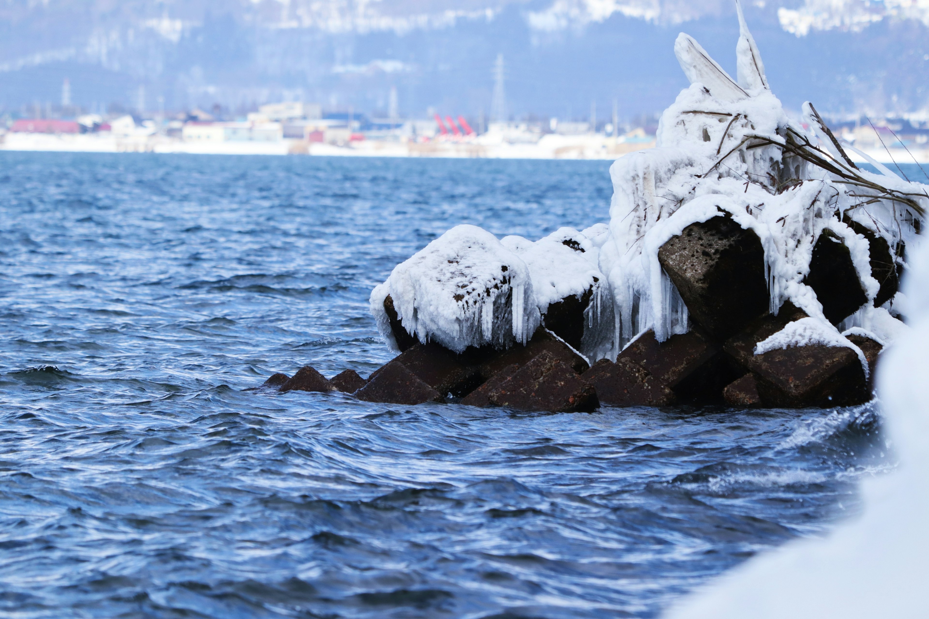 Frozen rocks covered with snow by the water's edge