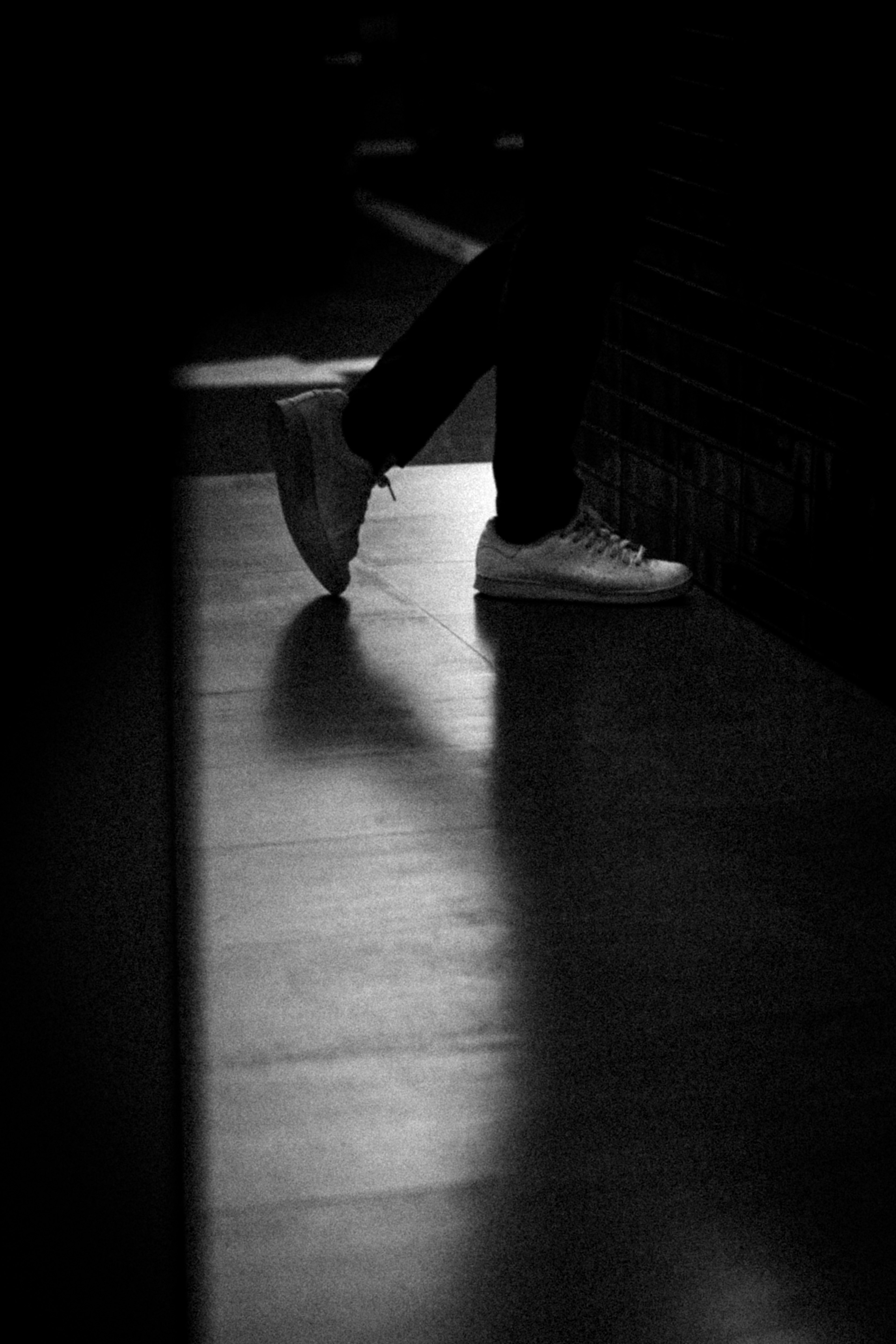 Silhouette of feet in white sneakers against a dark background