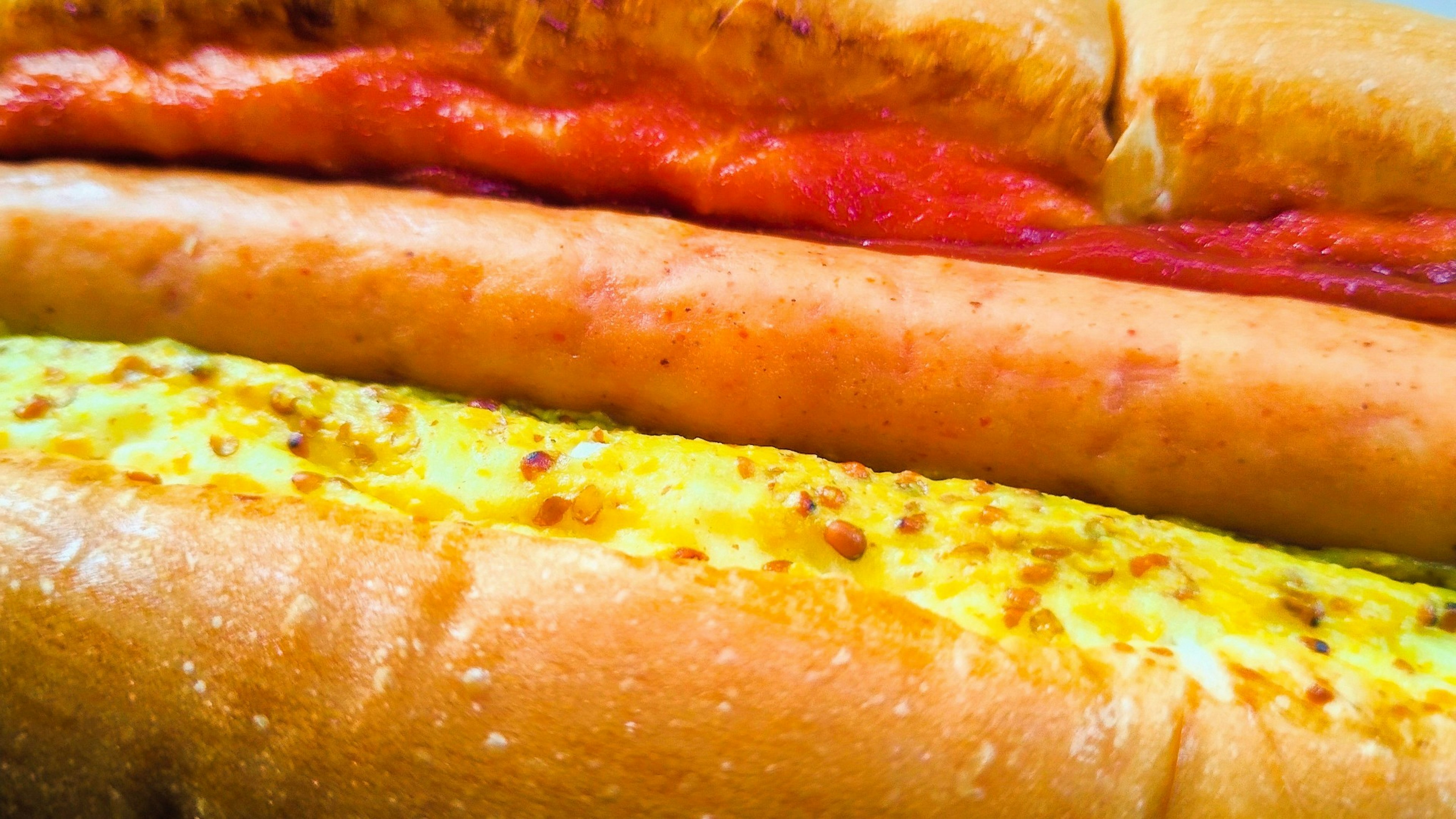 Tres sándwiches de hot dog apilados con diferentes condimentos