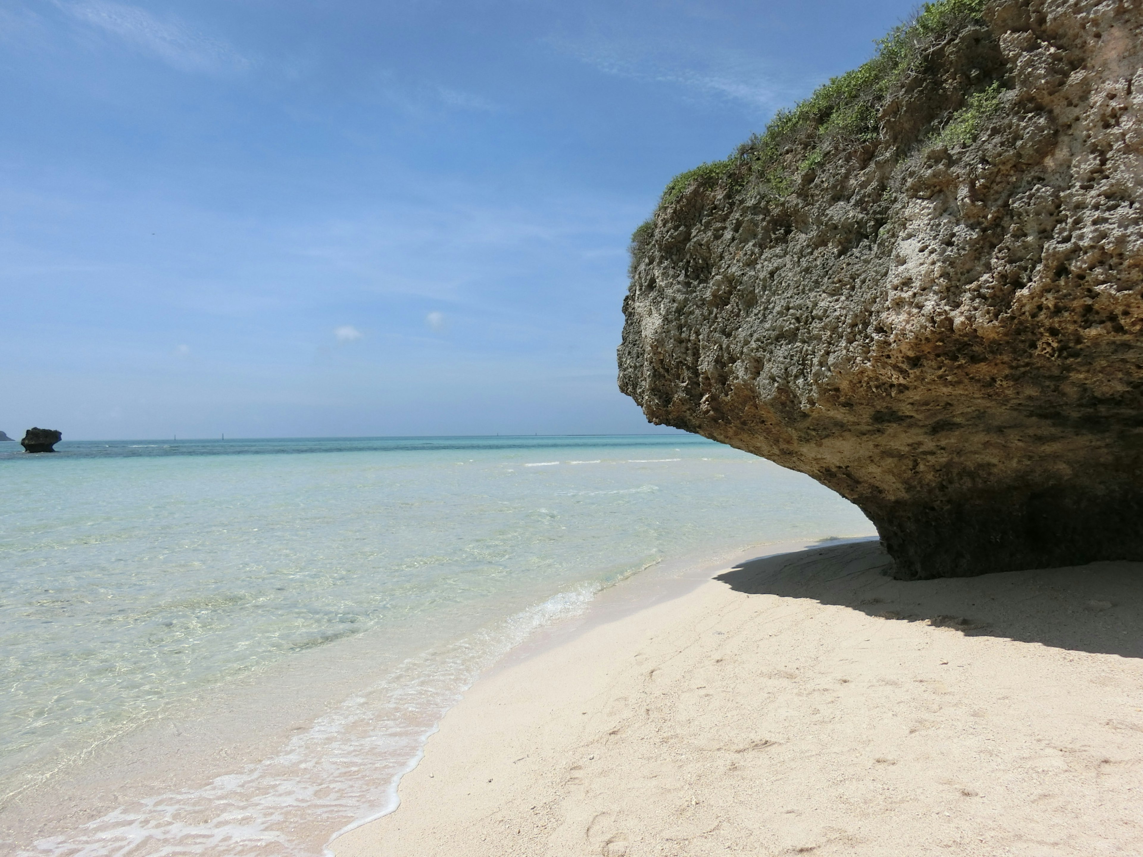 Hermosa escena de playa con formación rocosa mar tranquilo y cielo azul