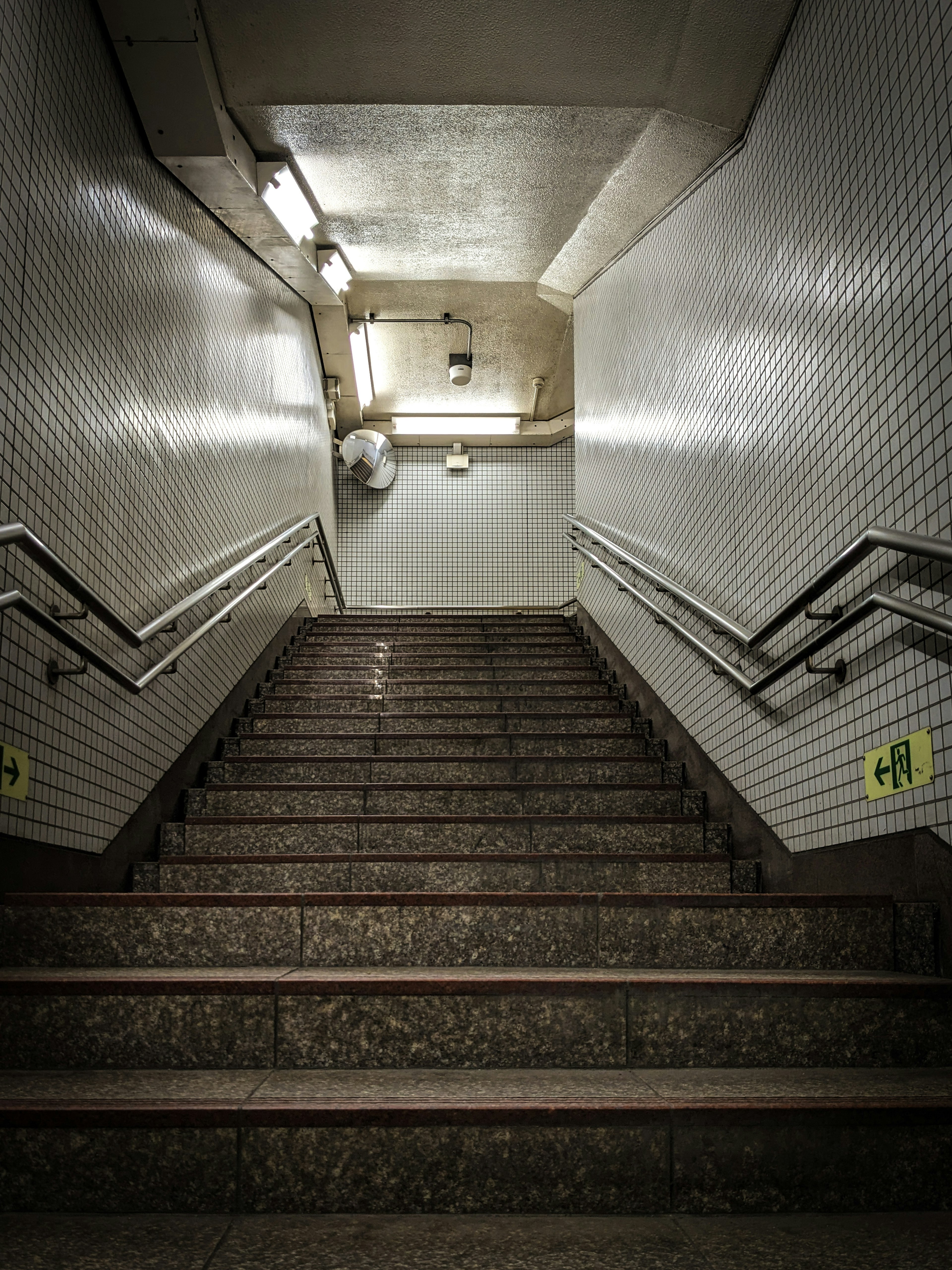 Dunkler Eingang zu einer U-Bahn-Treppe Helle Beleuchtung und geflieste Wände