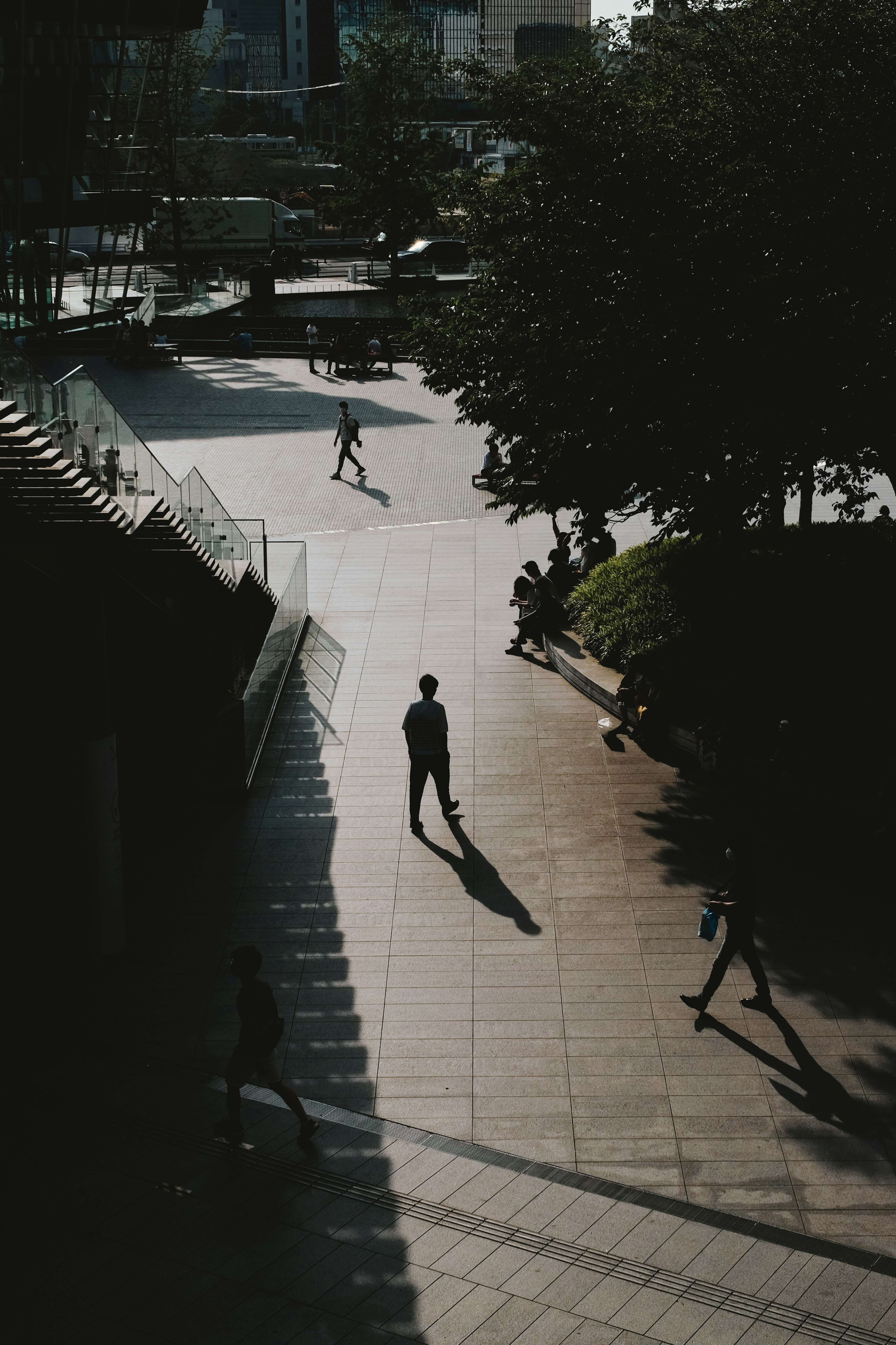 人々が歩いている都市の風景の中で立つ一人の人物の影