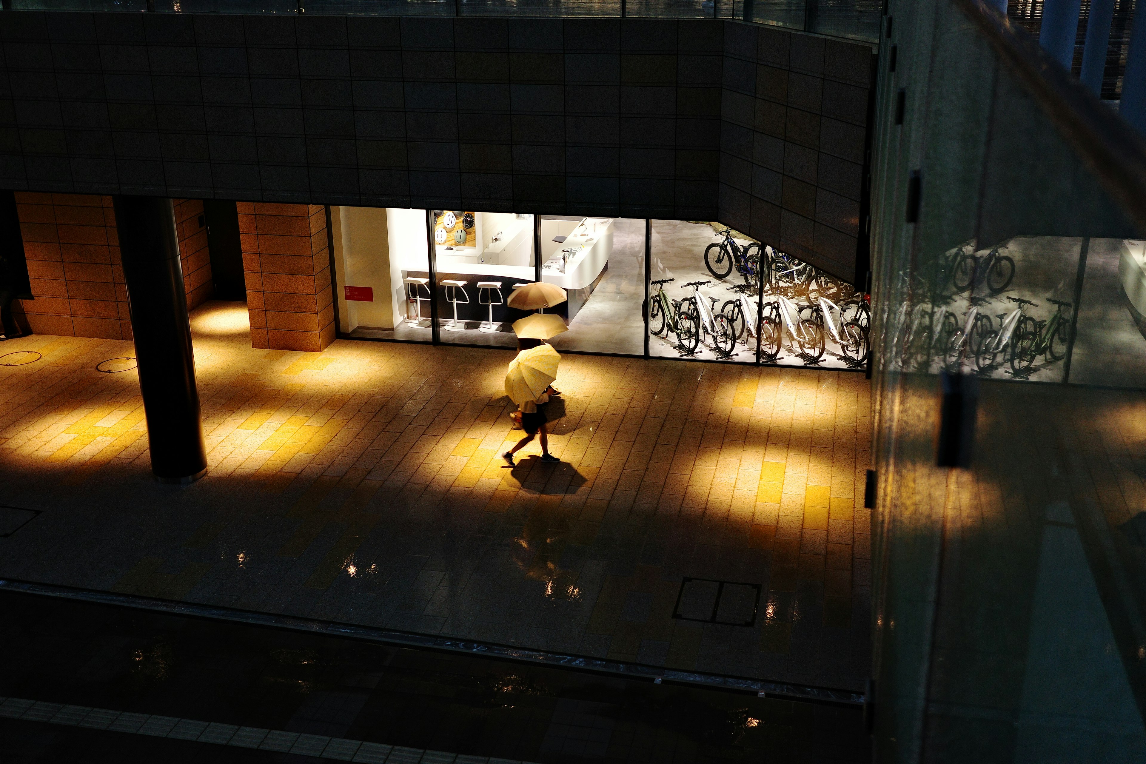 Silhouette of a person with an umbrella walking in a dark corridor with bright windows