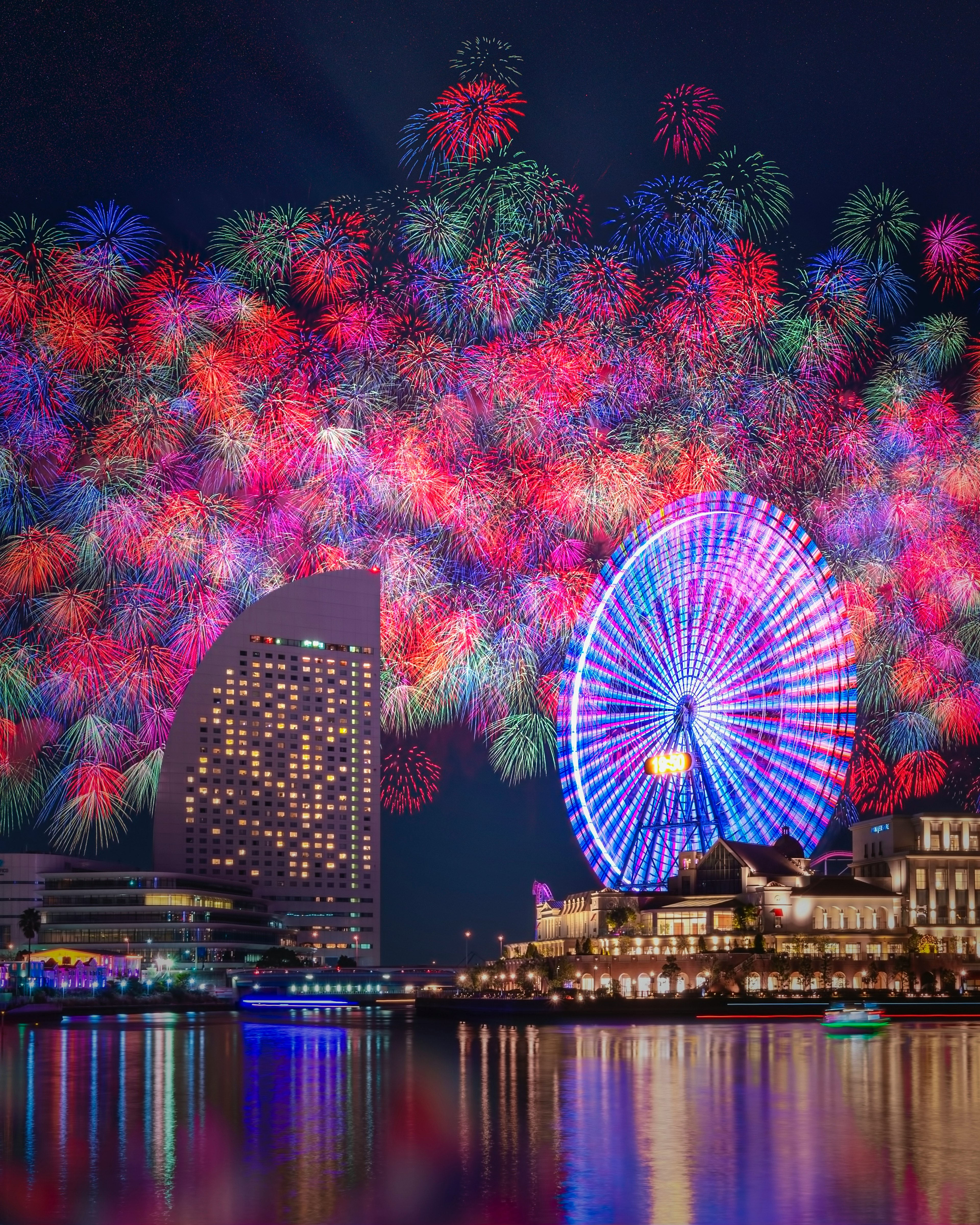 夜空に広がるカラフルな花火と観覧車のある美しい都市の景色