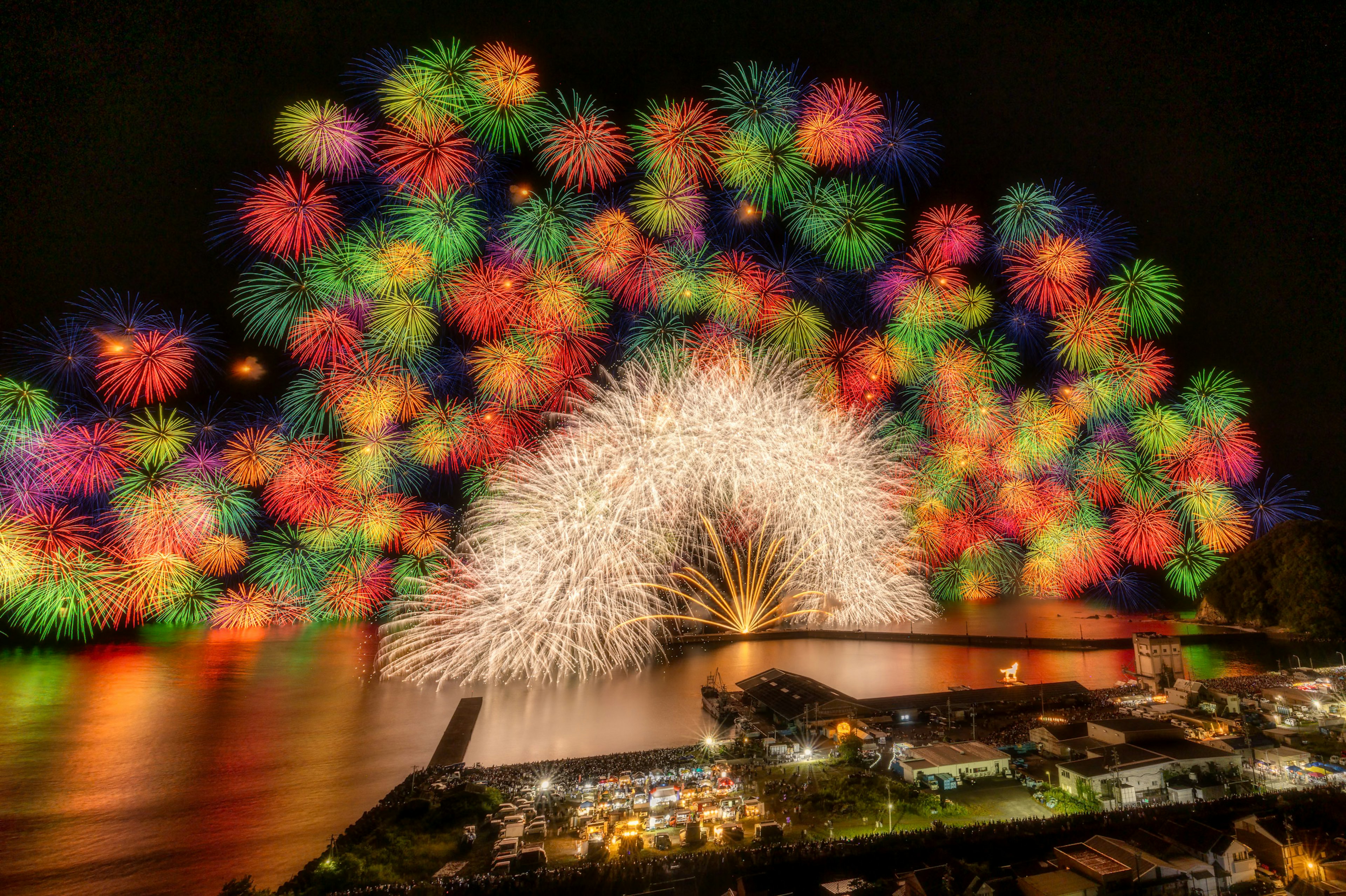 夜空に広がる色とりどりの花火と川の景色