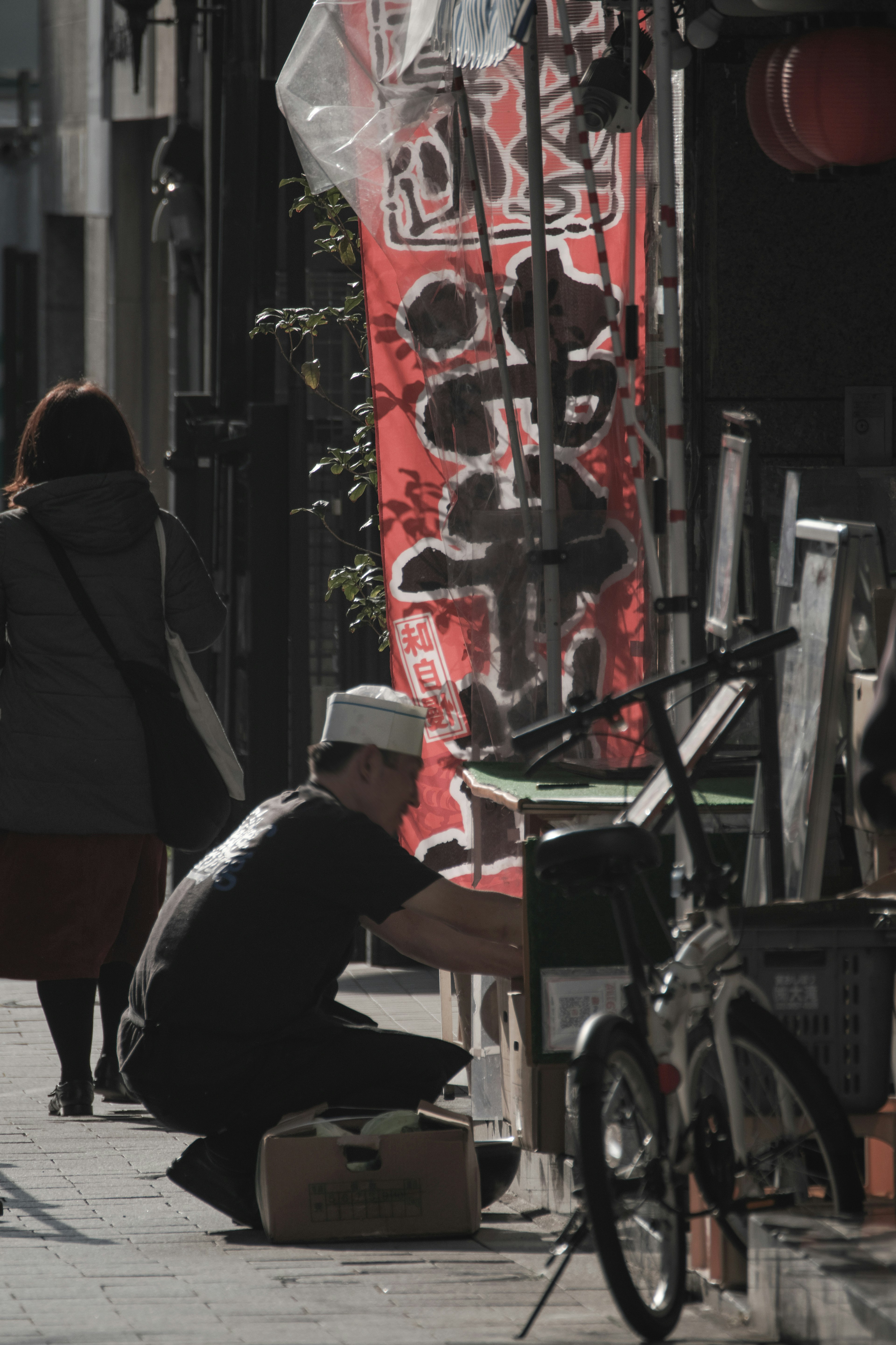 Hombre trabajando en la calle con una pancarta roja de fondo