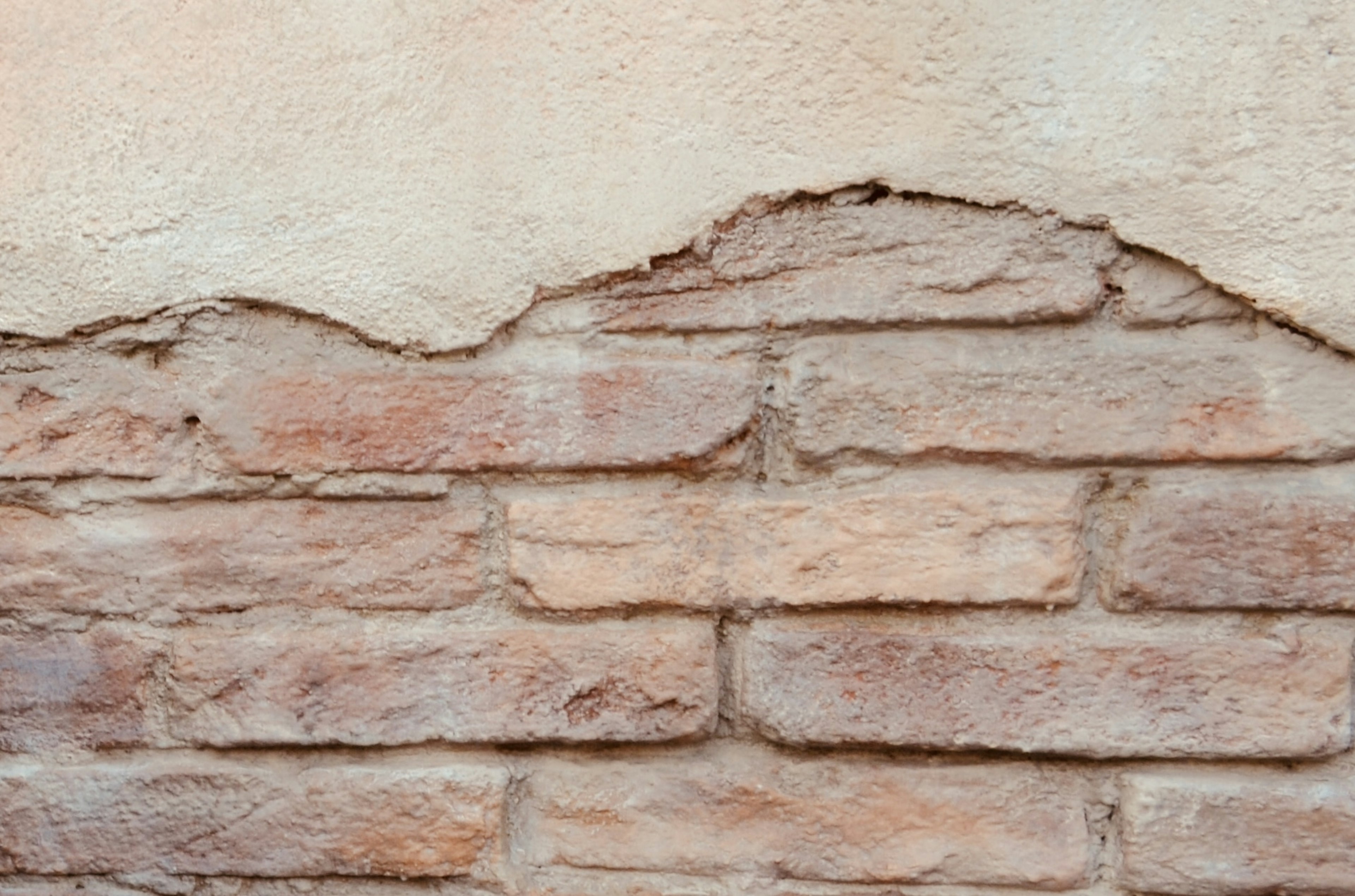 Ein Teil einer strukturierten alten Backsteinmauer blättert ab