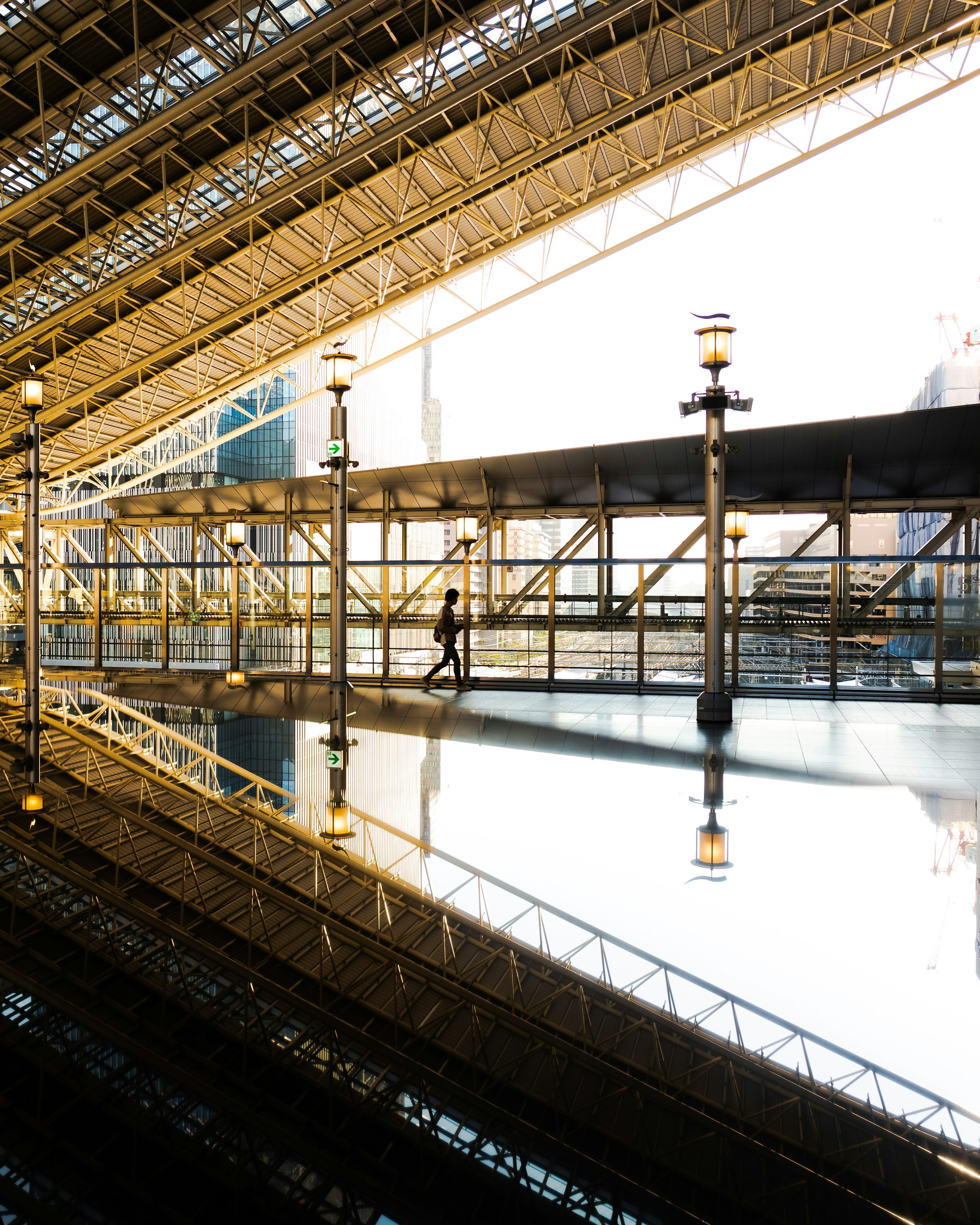 A person walking in bright light within a modern architectural space reflecting on the floor