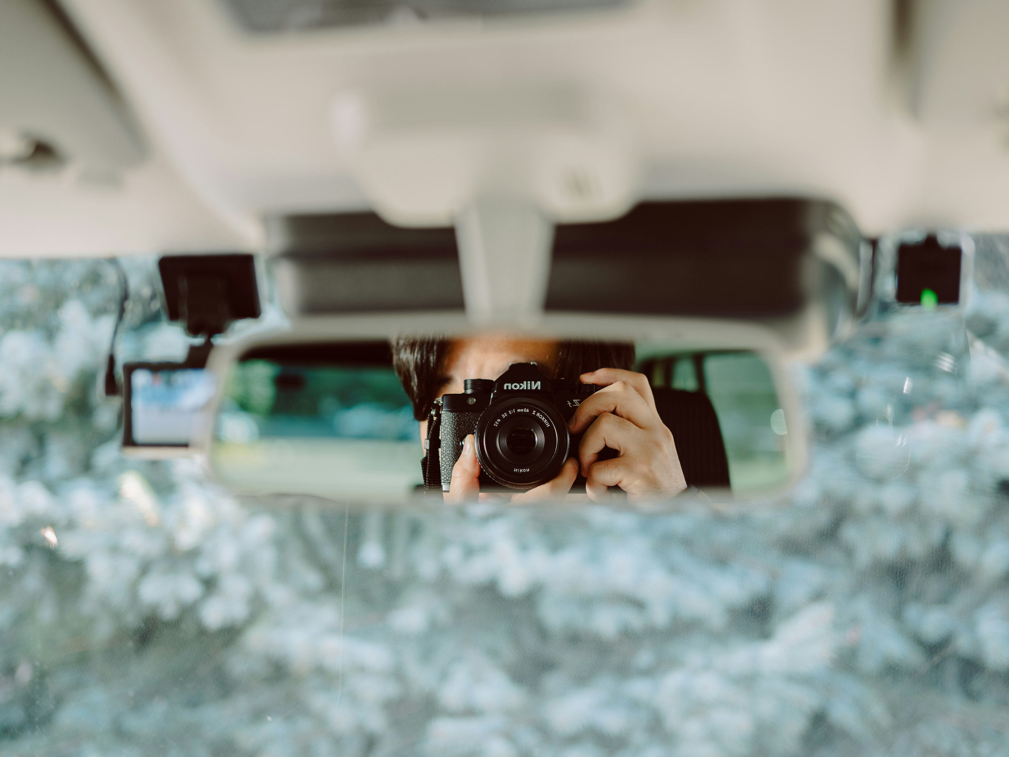 Riflesso di una persona che tiene una macchina fotografica nello specchietto di un'auto