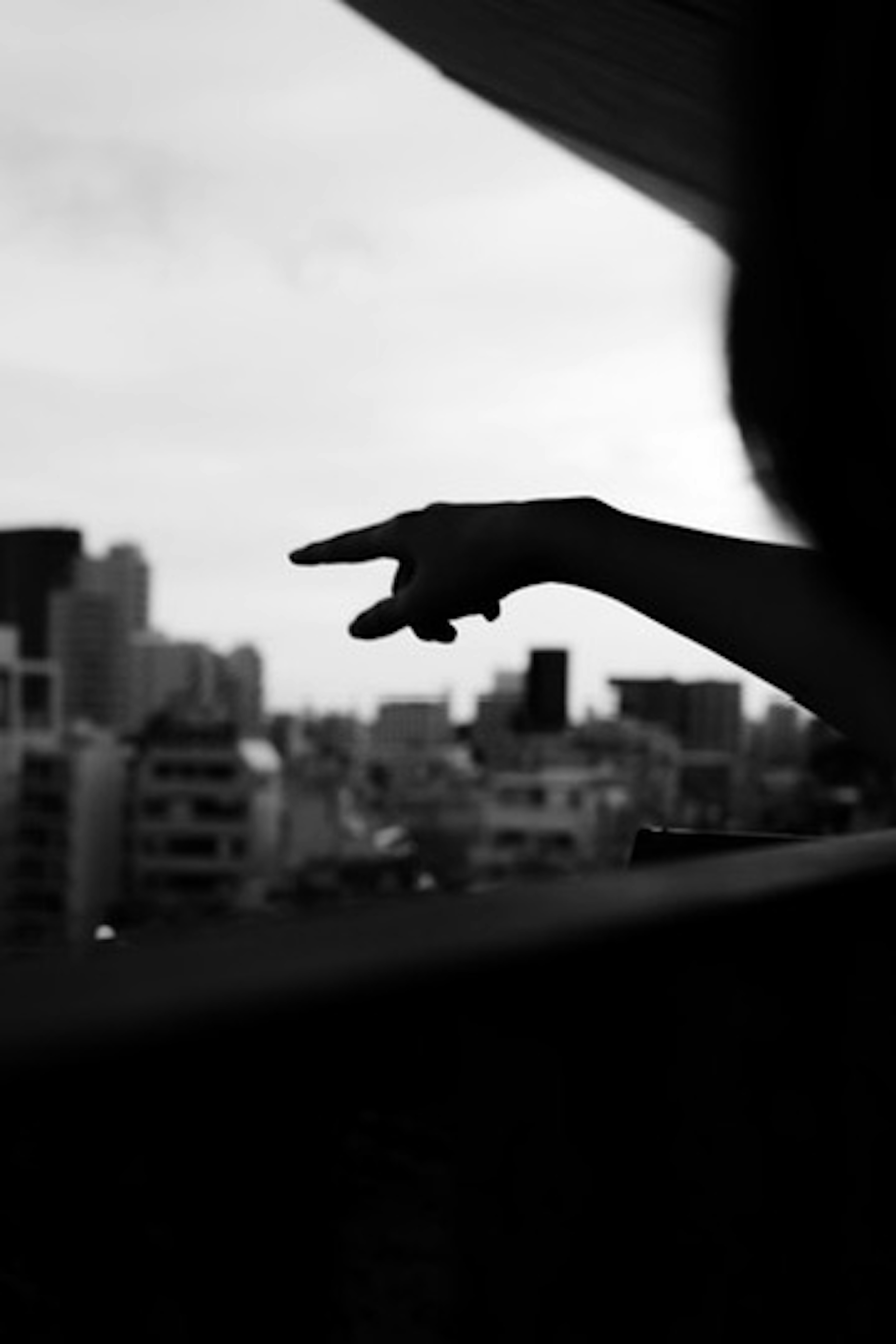 Silhouette einer Hand, die auf eine Stadtsilhouette im Hintergrund zeigt