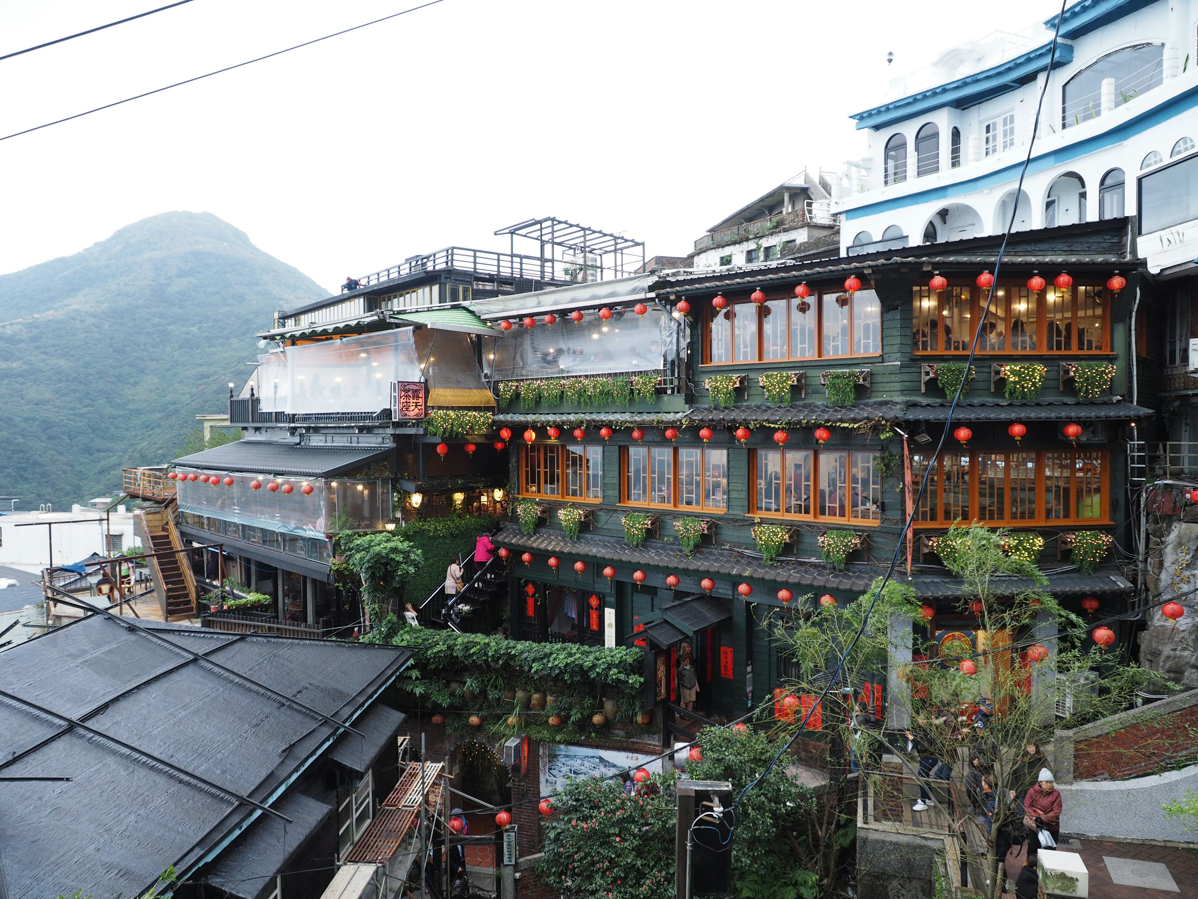 被山脉和绿植环绕的传统台湾建筑，装饰有红色灯笼