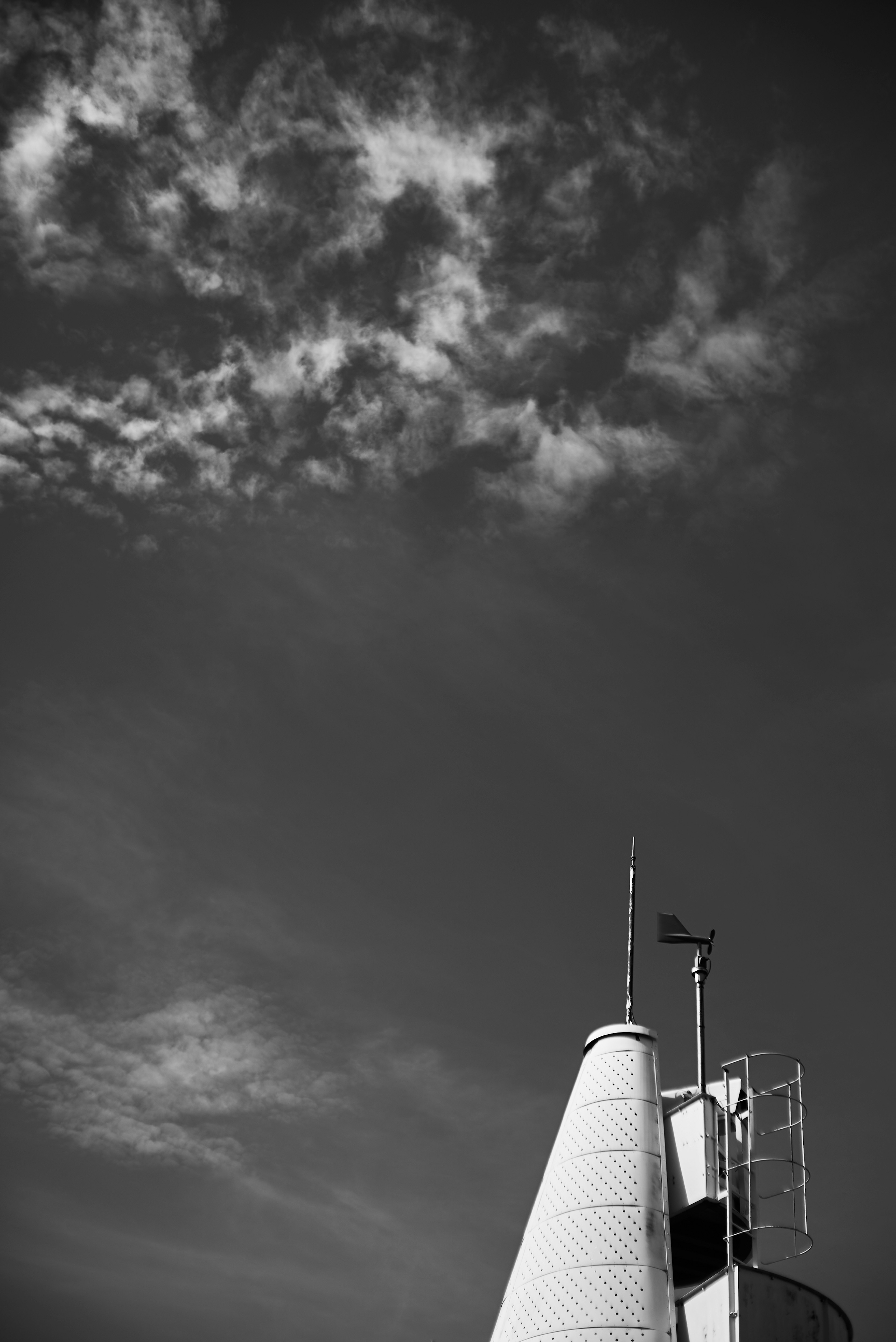 Imagen en blanco y negro de nubes en el cielo con una estructura puntiaguda