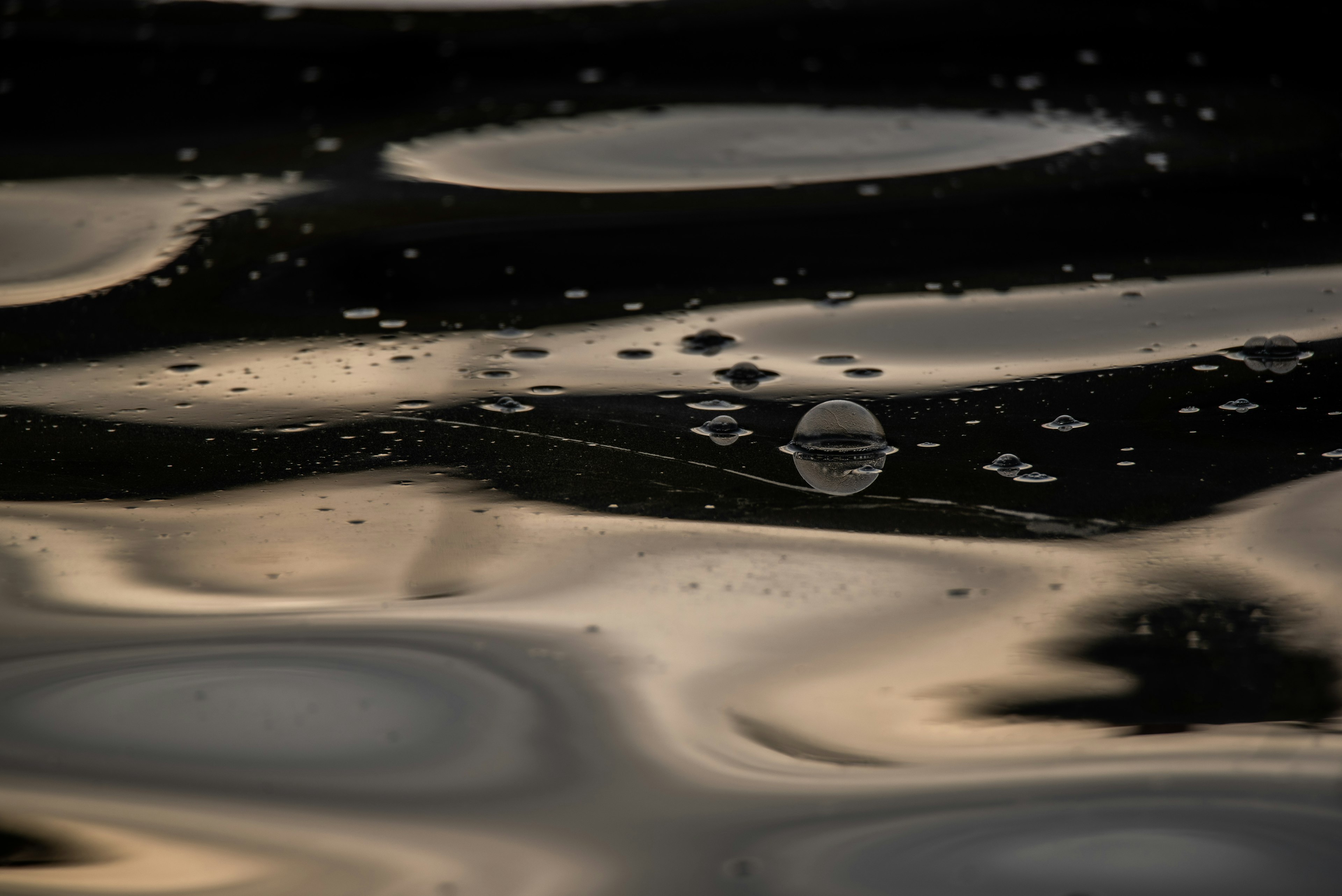 Imagen de agua oscura con reflejos y burbujas