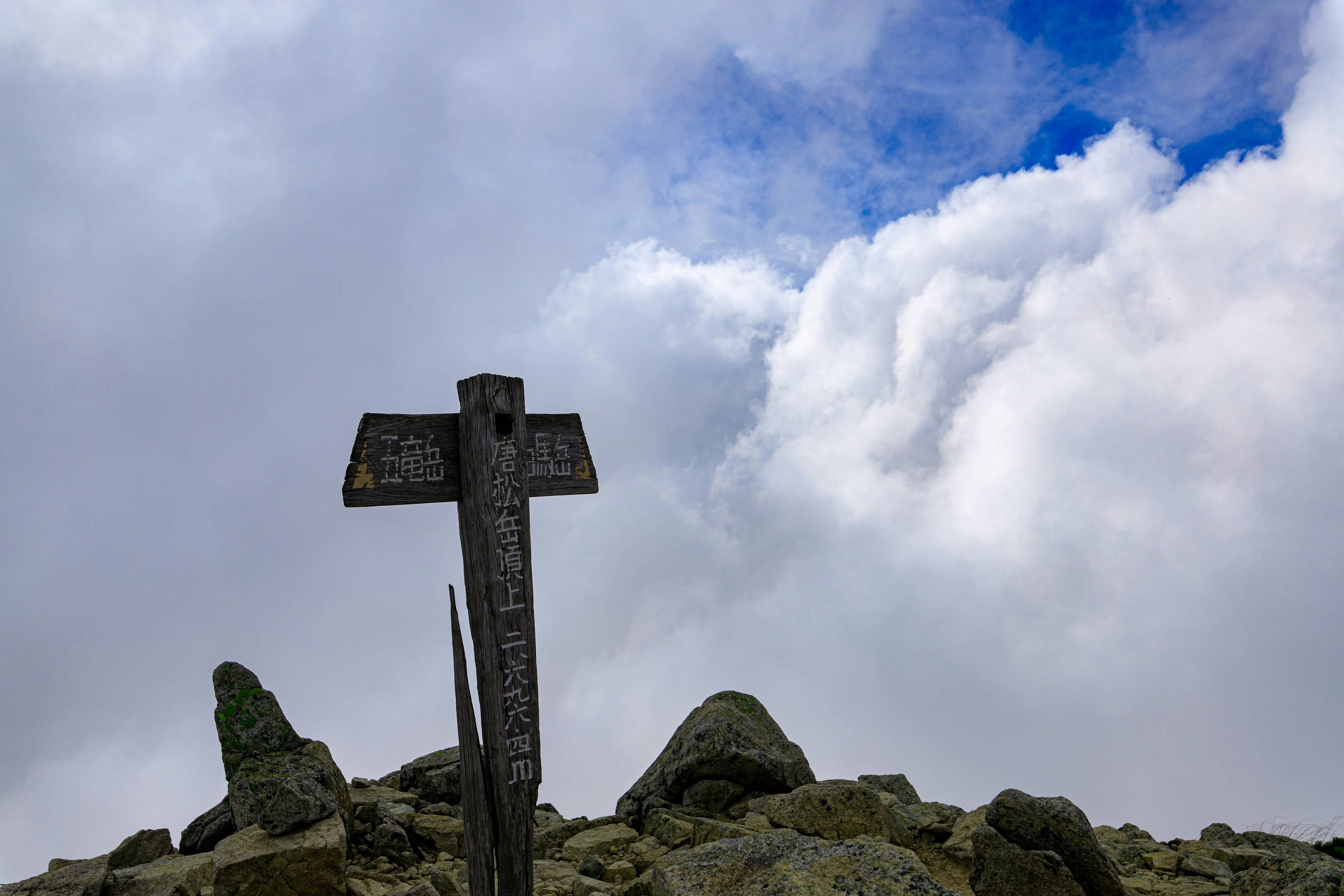 Schild auf dem Gipfel des Berges mit bewölktem Himmel