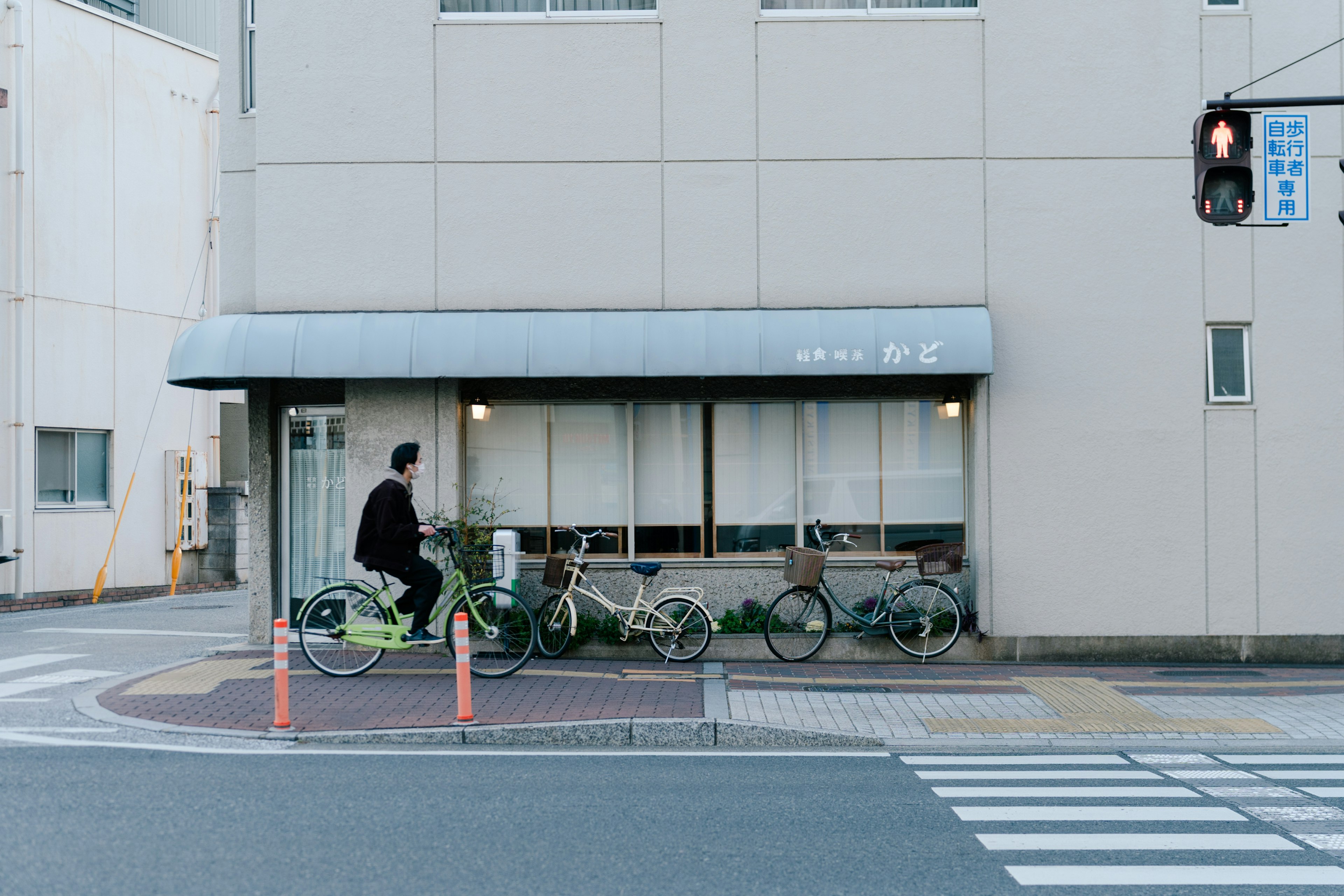 Un hombre montando una bicicleta cerca de un café con un exterior sencillo