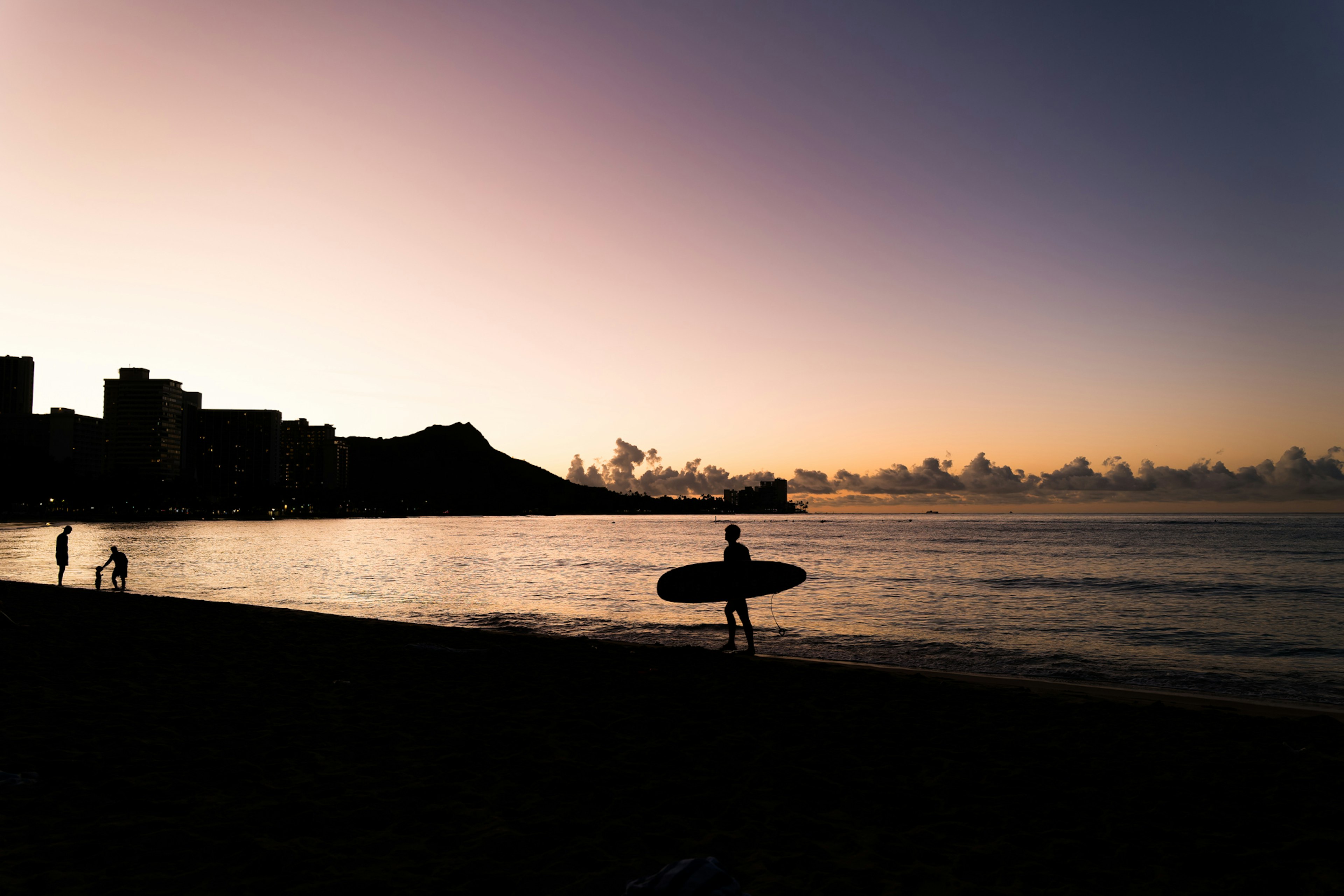 Silueta de un surfista sosteniendo una tabla de surf en una playa al atardecer