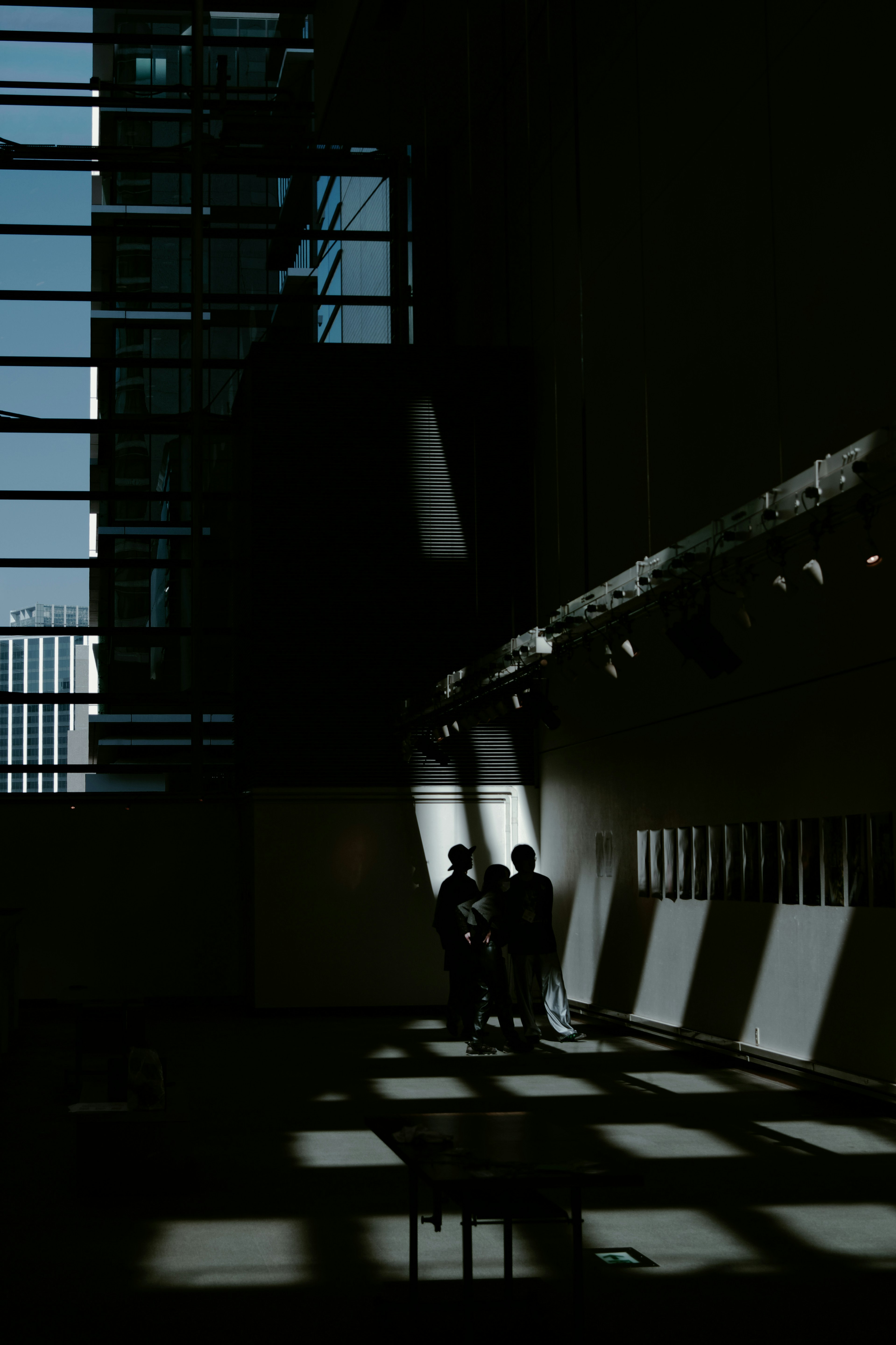 Silhouettes of two people in a dark space with light streaming through a window