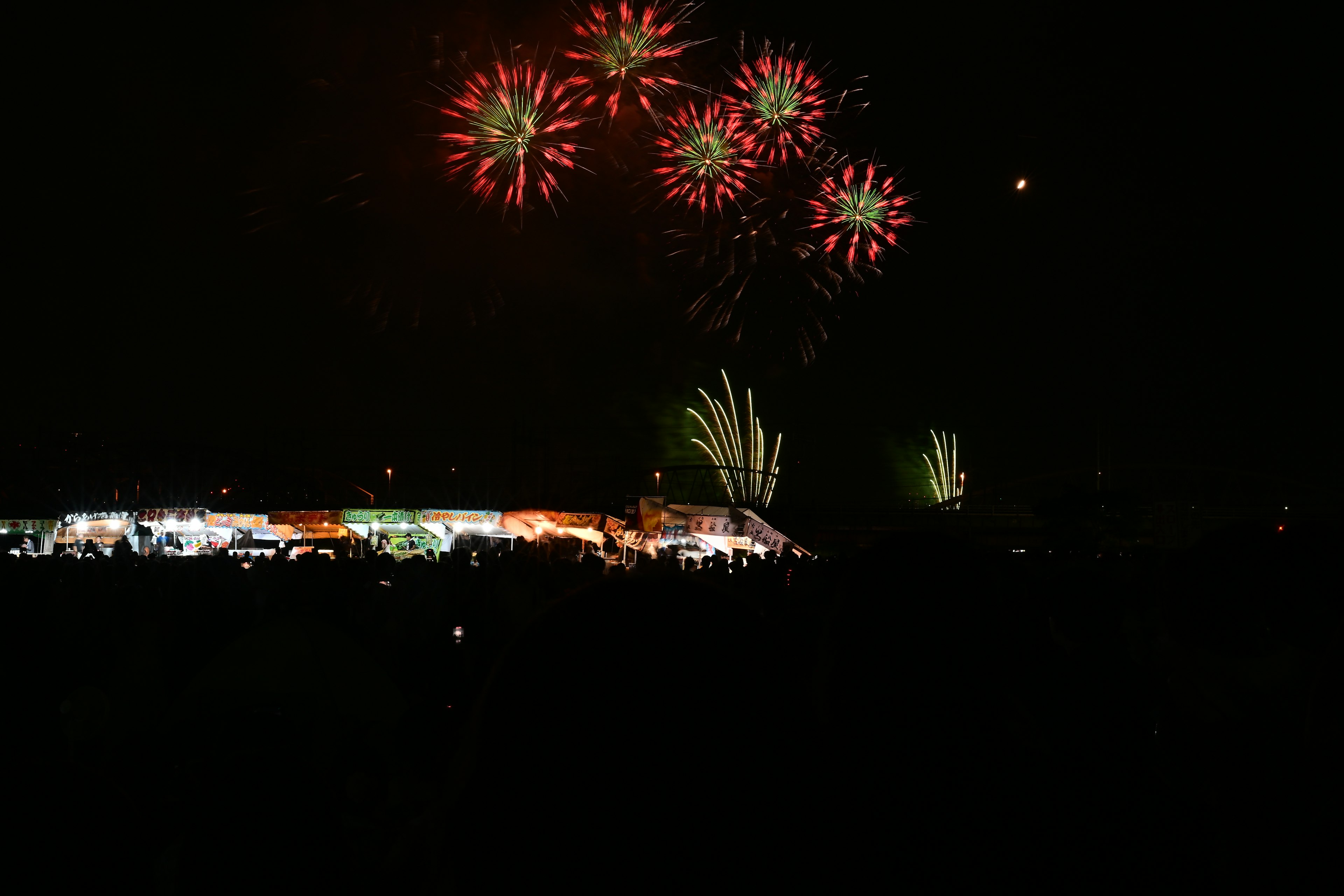 夜空に花火が打ち上げられ観客が楽しむ光景