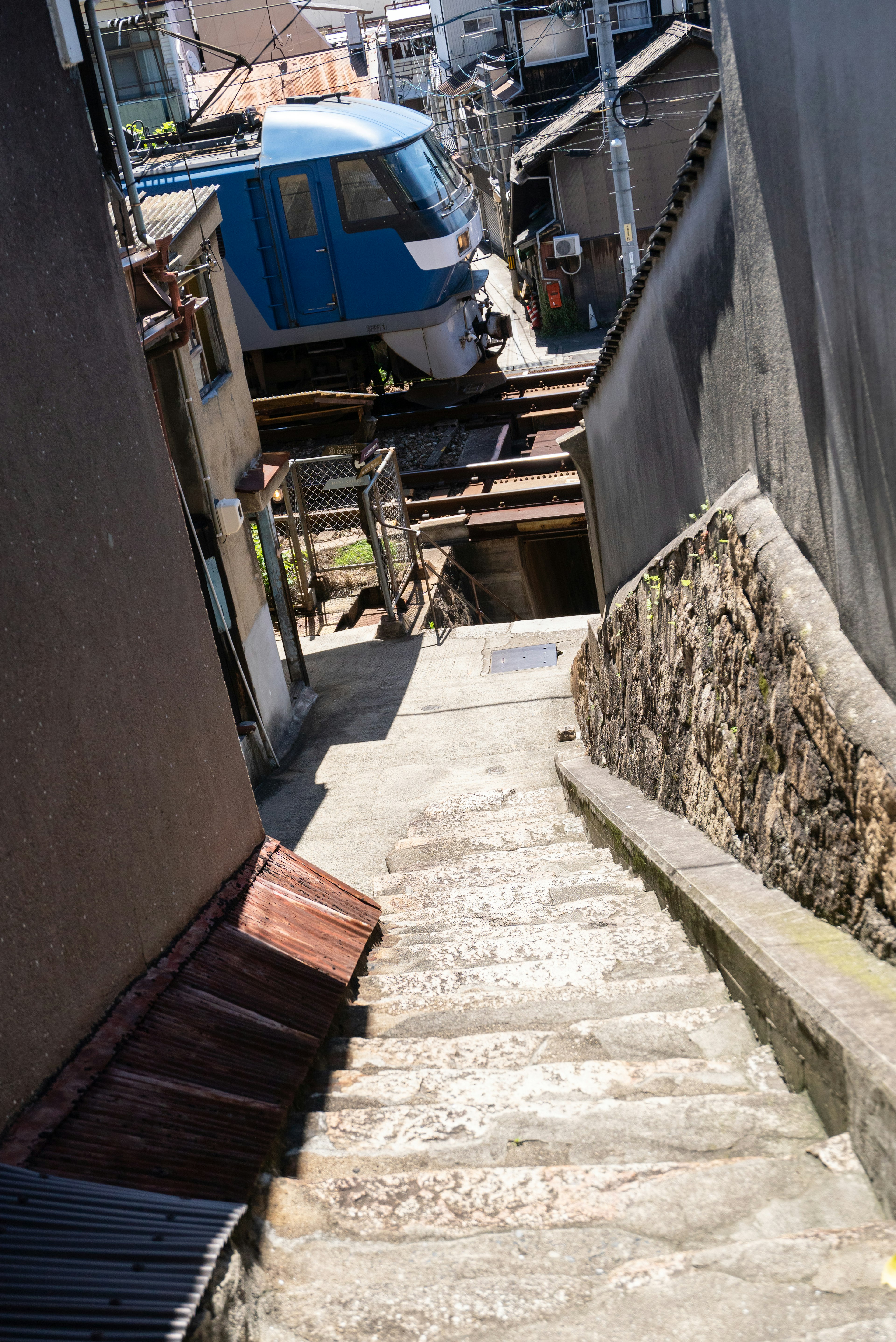 Vue d'une rue étroite avec des escaliers et des voies de train visibles