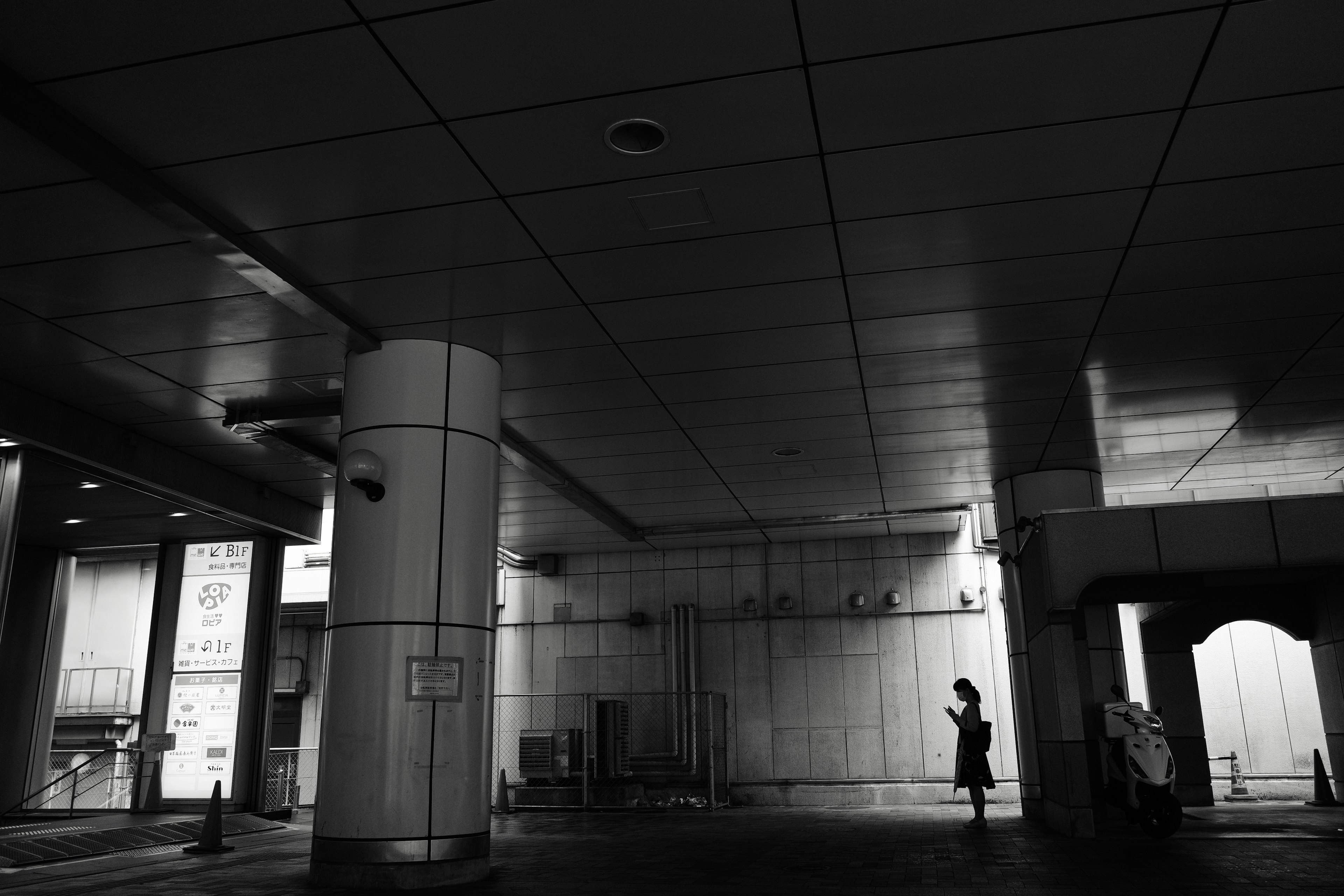 Silhouette di una persona in piedi in uno spazio buio con architettura moderna